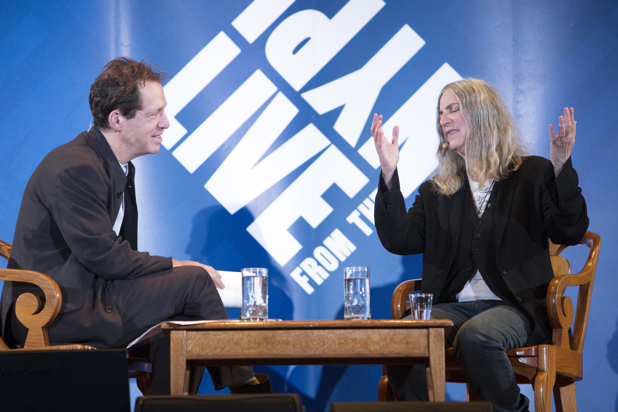 Paul Holdengråber sitting on stage along with Patti Smith as he interviews her.
