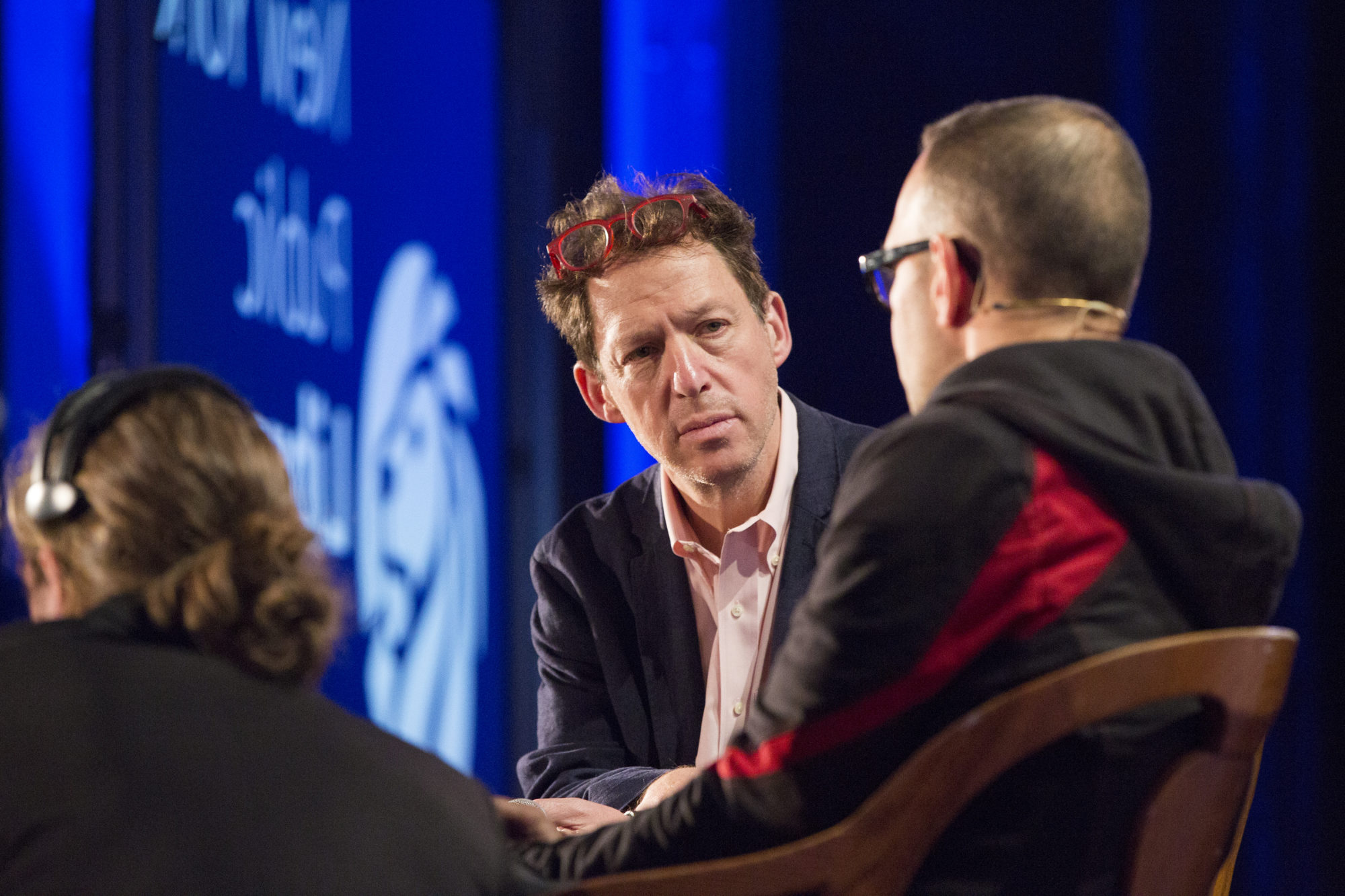 Paul Holdengräber giving a serious look onstage as he listens to someone he's interviewing.