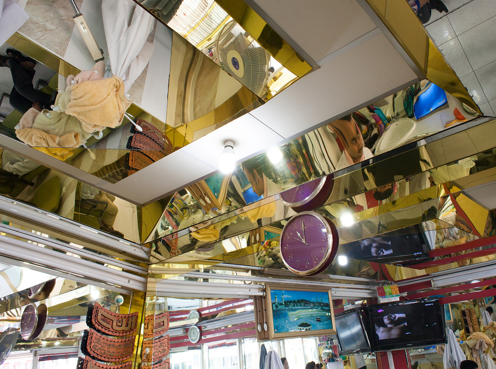 Mirrored ceiling reflects a distorted view of the objects and people in the room below, including a TV, blankets, and a purple and gold wall clock.
