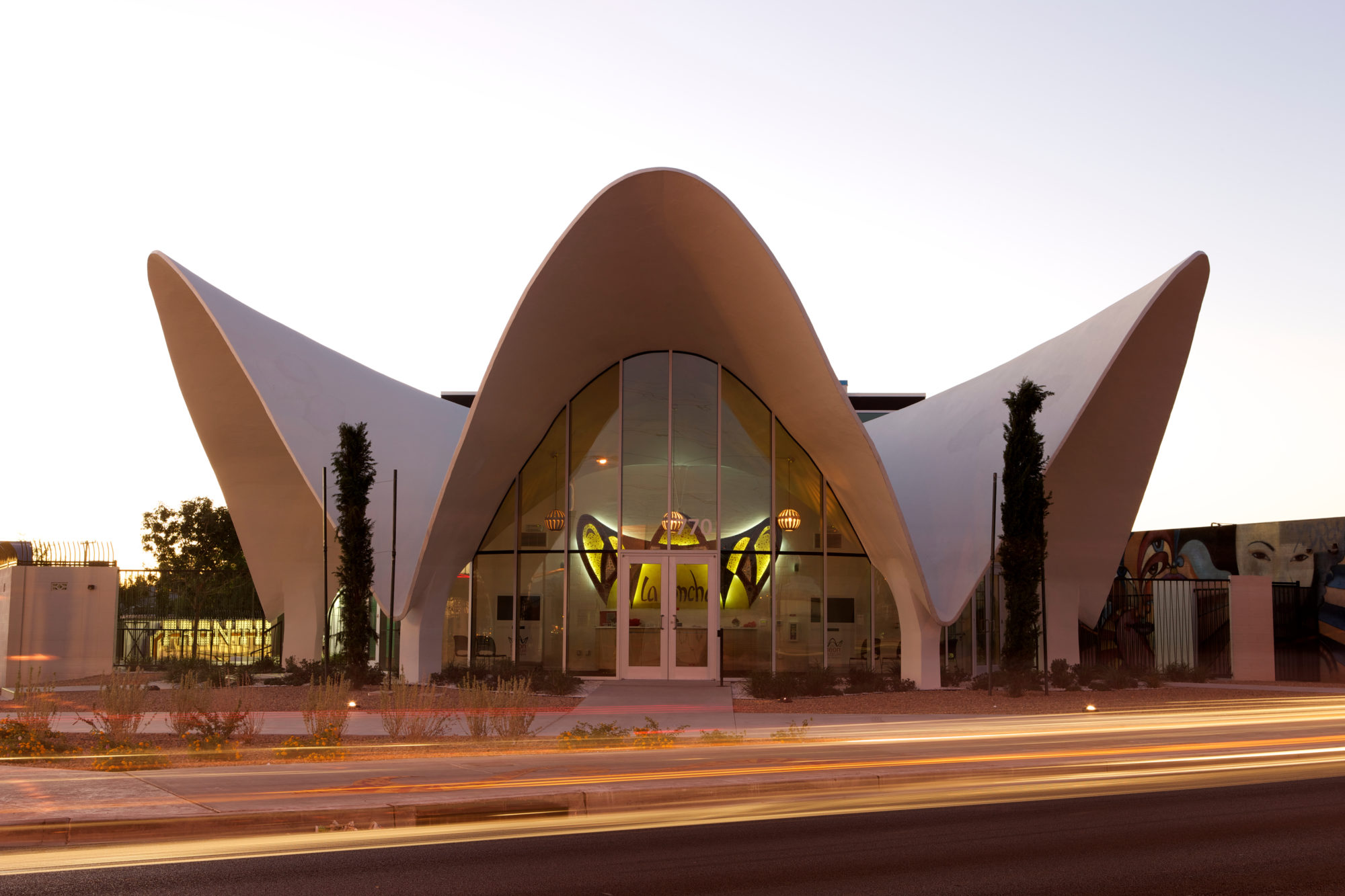 building with three triangular arches and glass front with yellow lit image inside