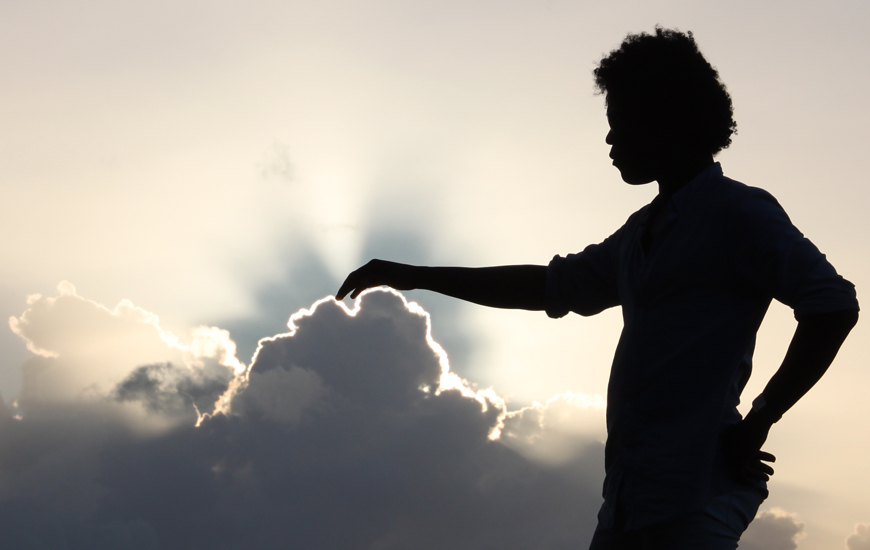 Silhouette of person touching top of a cloud