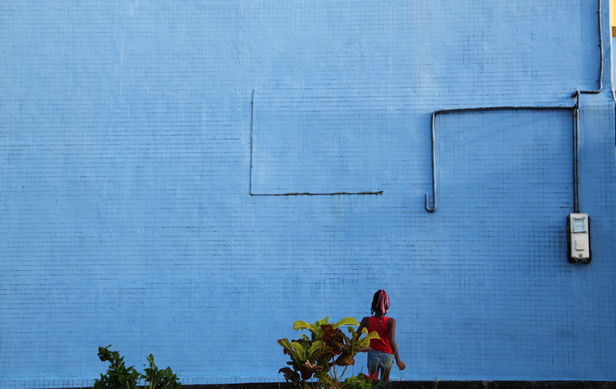 A girl in red faces a blue wall