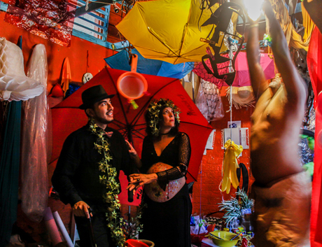 A man and woman look on as a man adjusts a light fixture in a colorful setting