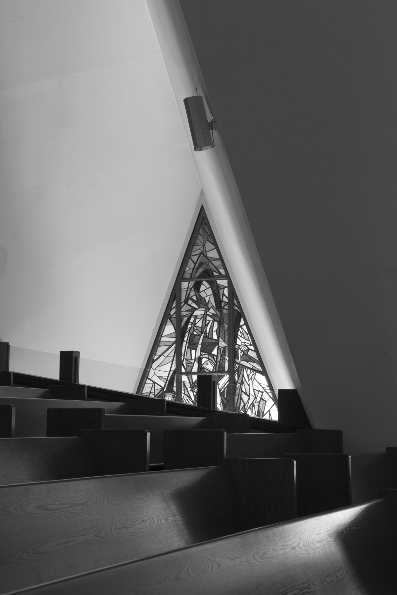Black and white architectural detail of pews and stained glass window in Guardian Angel Cathedral