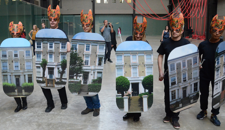 Six people wearing colorful masks and holding cutouts of a building