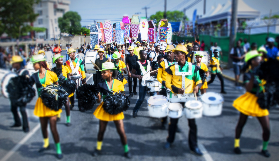 A drumline and cheerleaders in a parade wearing green yellow and black
