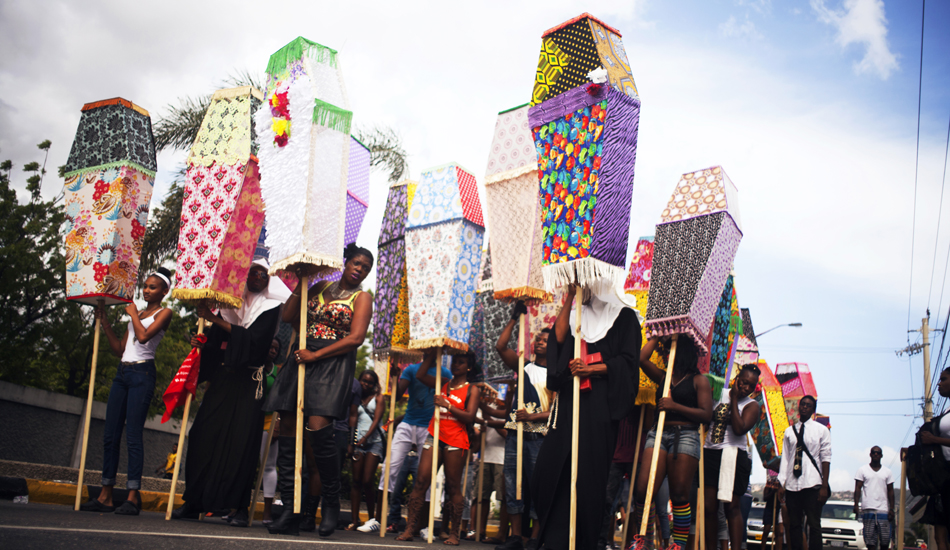 A group of people walking and holding poles that have decorative lamp shades on them