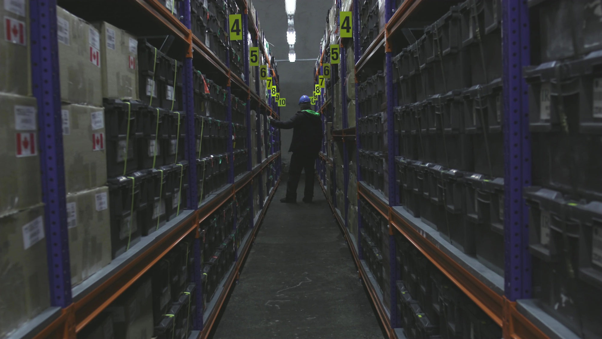 video still of a construction worker looking at items inside a factory