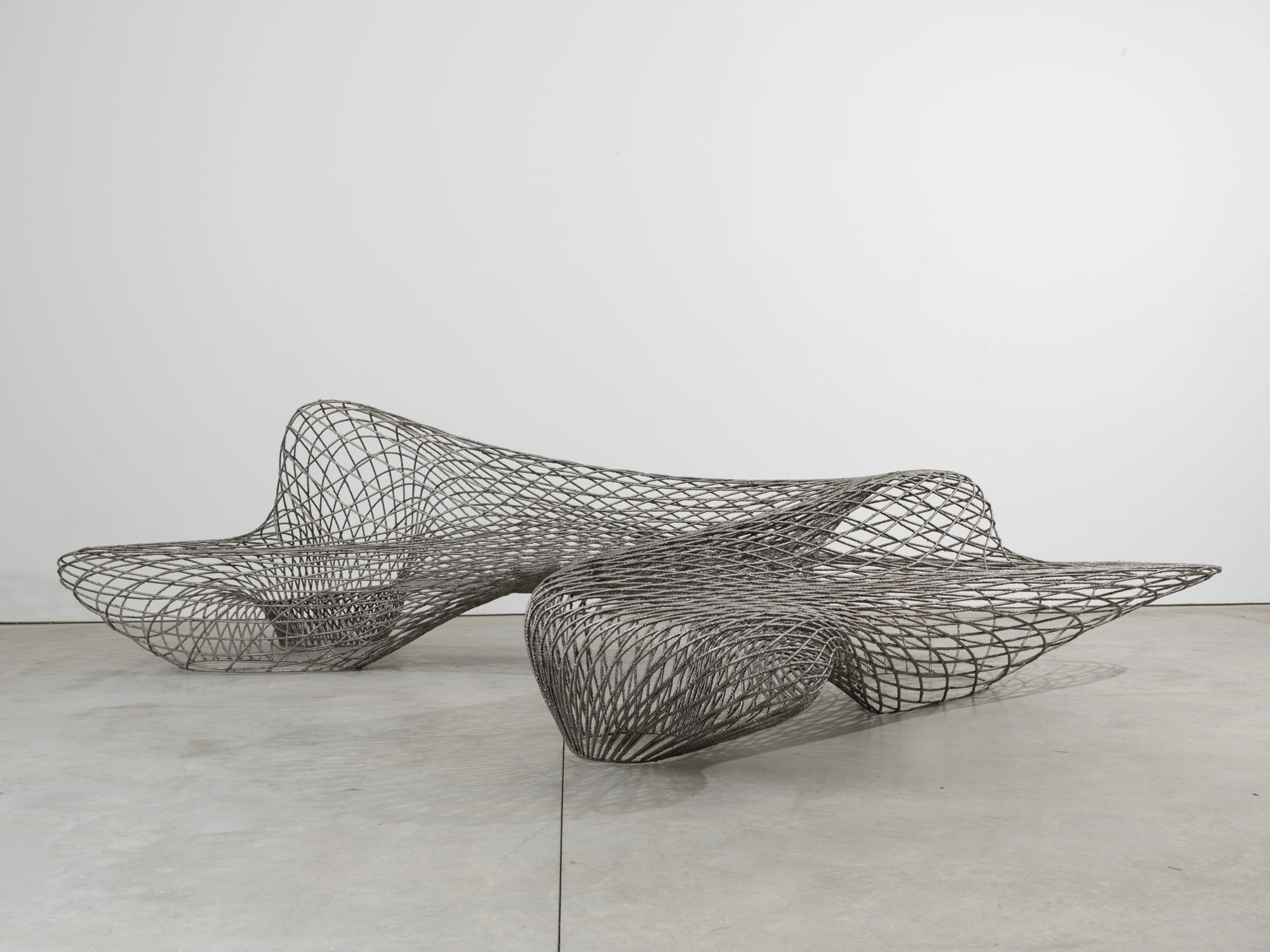 a curving silver bench of metal mesh squares