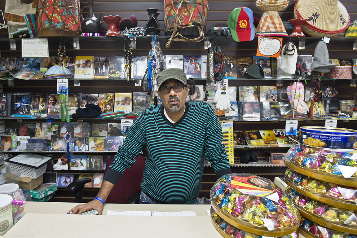 a man in a green shirt behind the counter of a shop