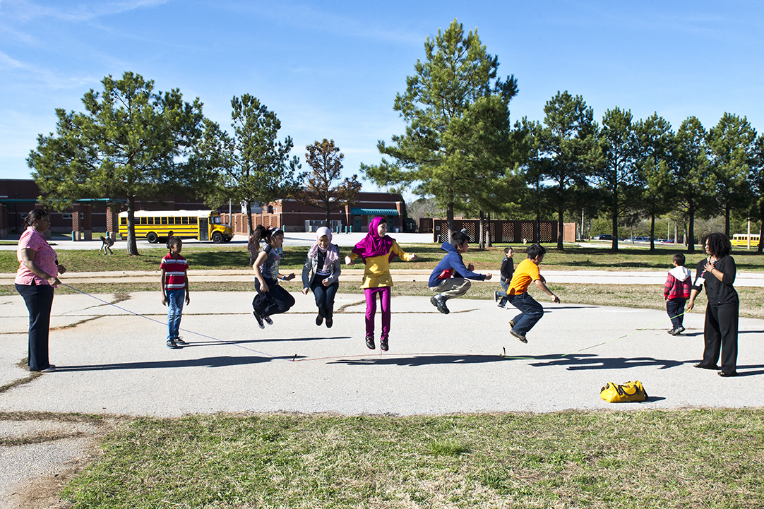 kids jumping a large rope on a sunny day