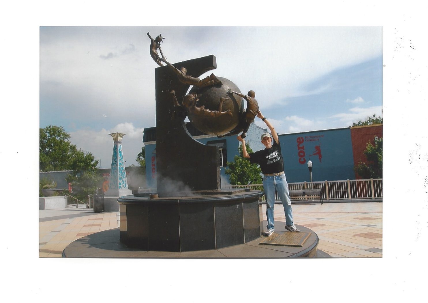 Brian Sherman, wearing blue jeans and black shirt while touching a large sculpture