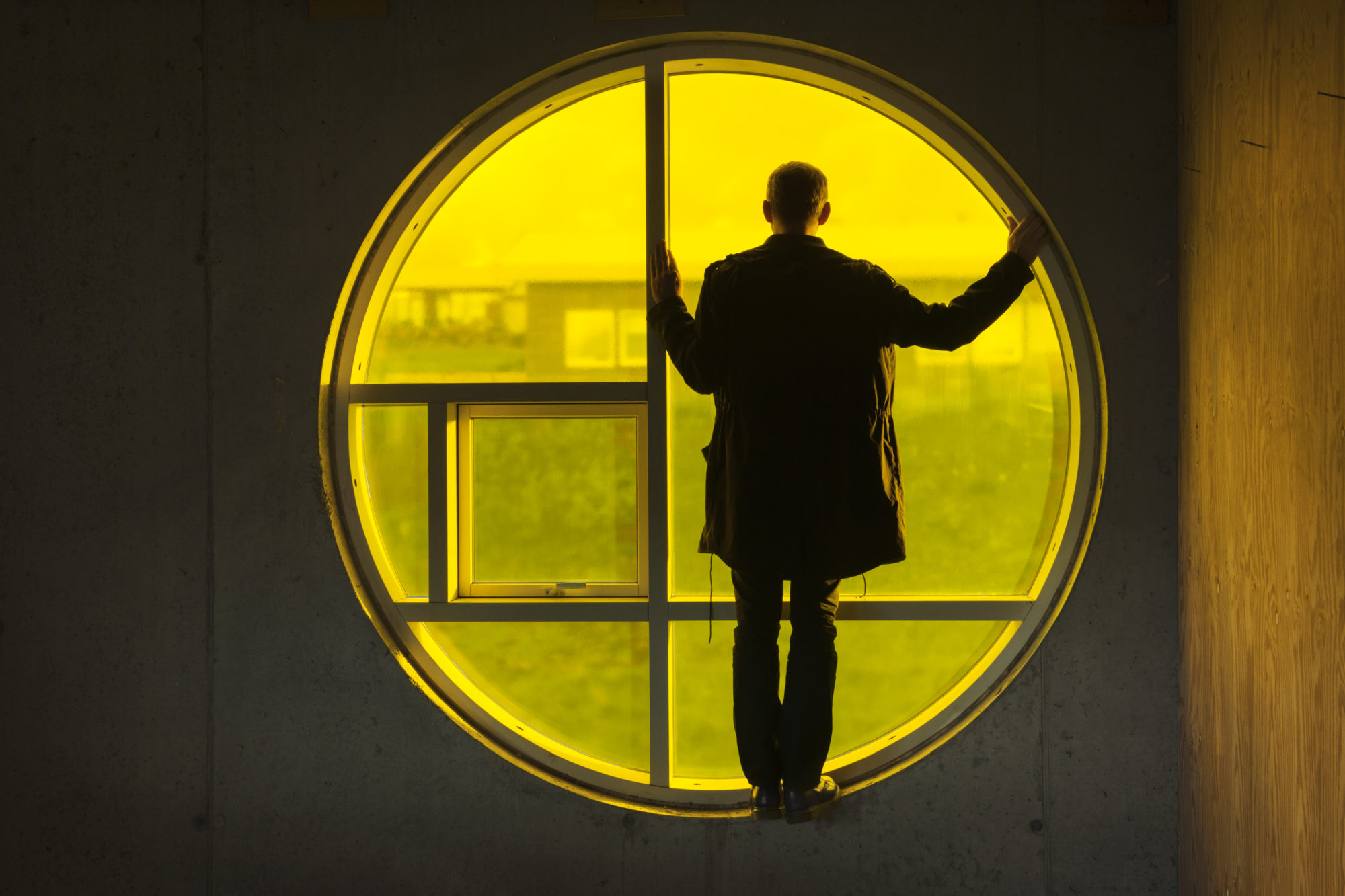 Man looking out of a yellow circular window with geometric pattern