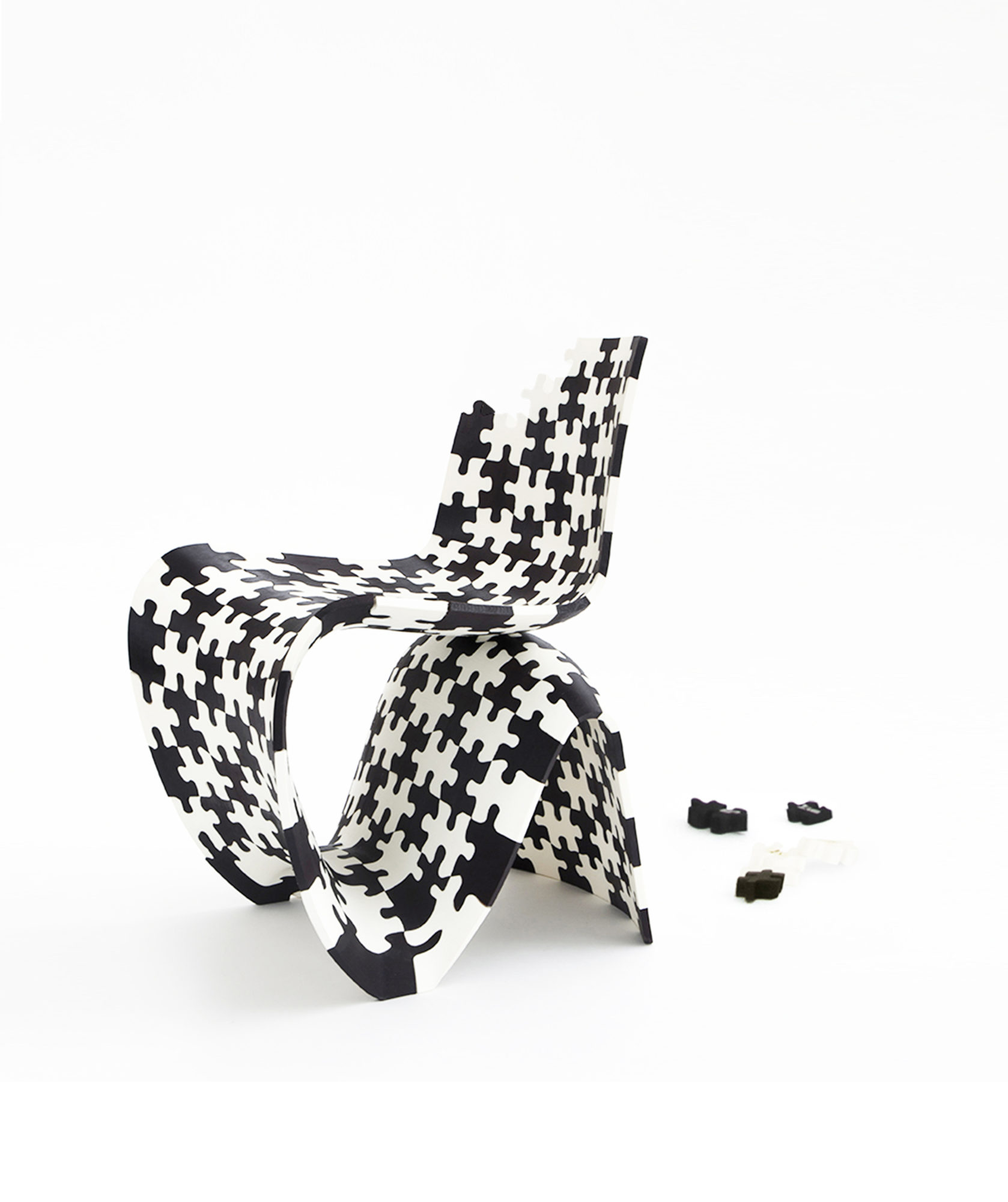 a black and white chair made up of puzzle pieces, with a few missing from a corner