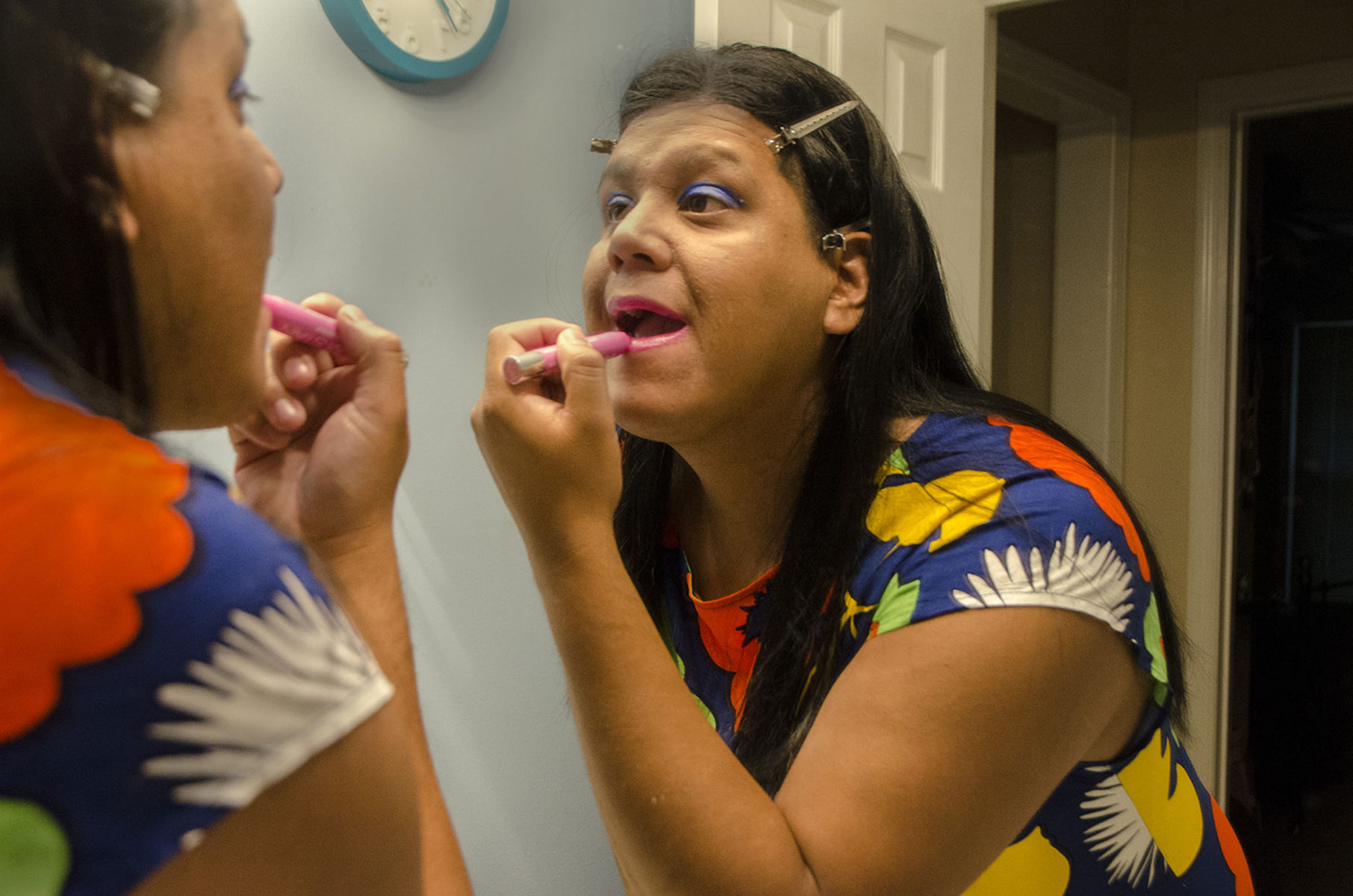 A woman puts lipstick on in a mirror