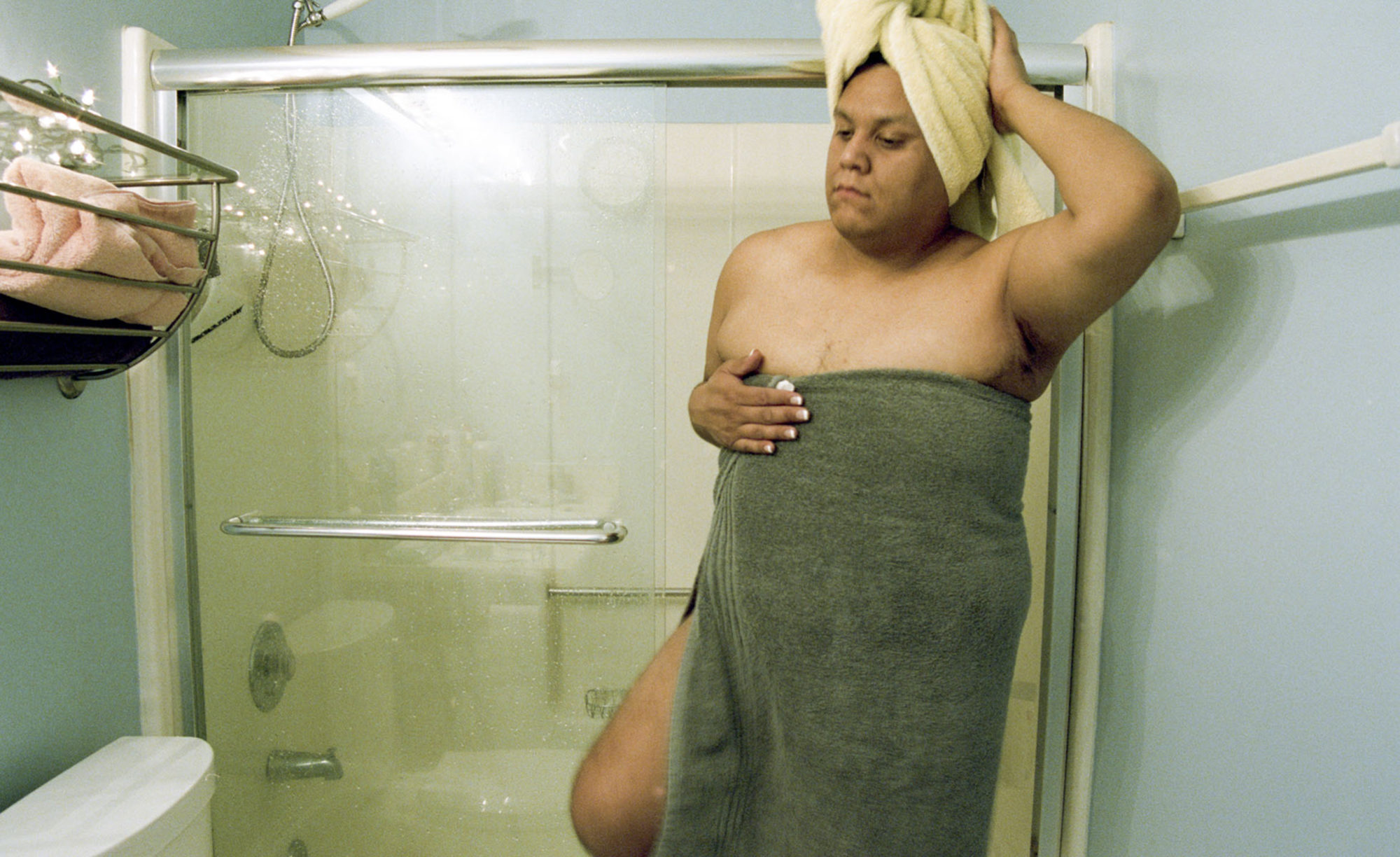 A person in a towel, getting out of the shower