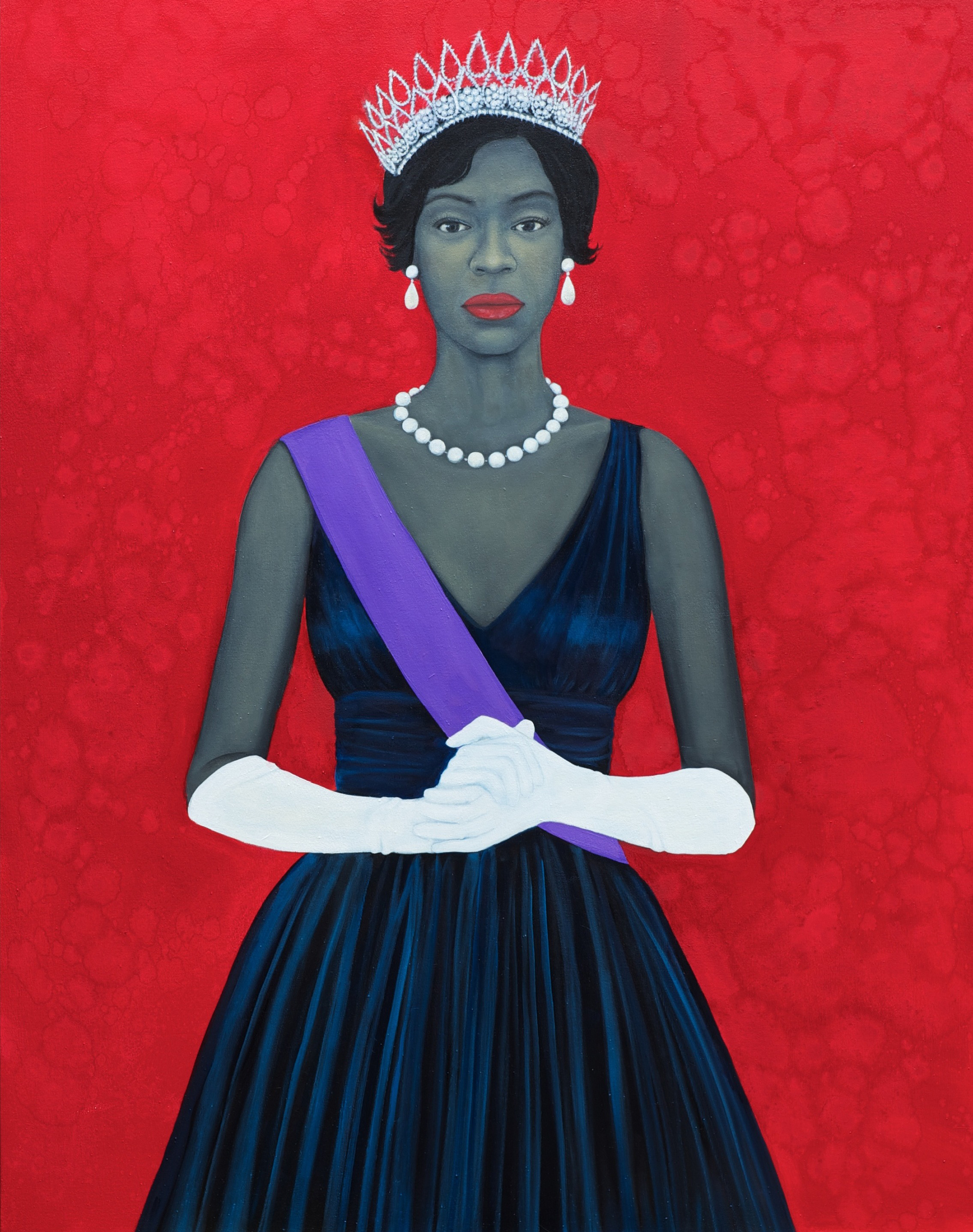 a woman standing, holding her hands in front of her, wearing a dark blue dress, white gloves, pearl jewelry and a tiara against a bright red background