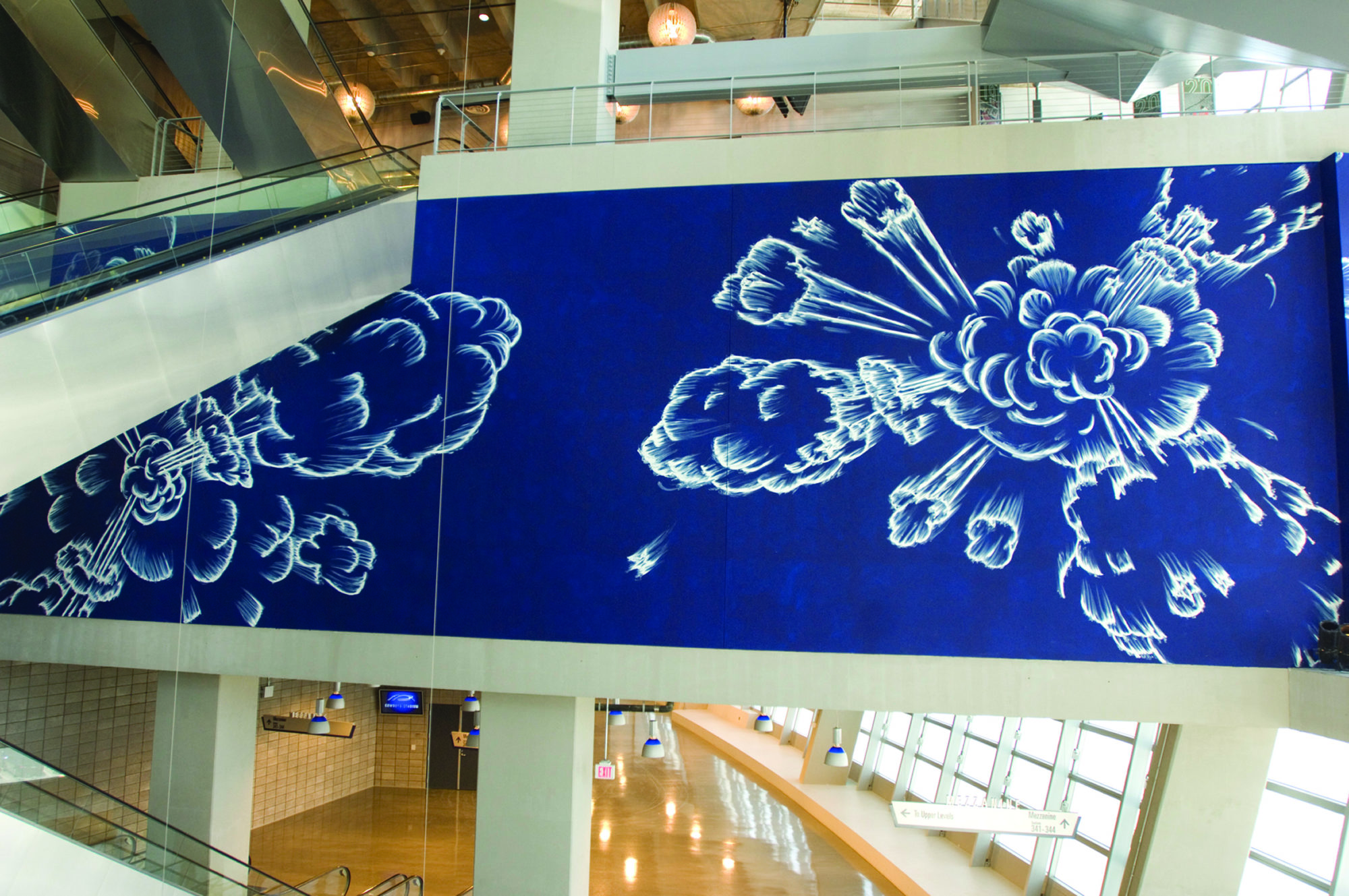 Gary Simmons' site-specific commission Blue Field Explosions is shown in the Northeast Monumental Staircase of the AT&T Stadium. Blue cloud shaped puffs appear to explode.