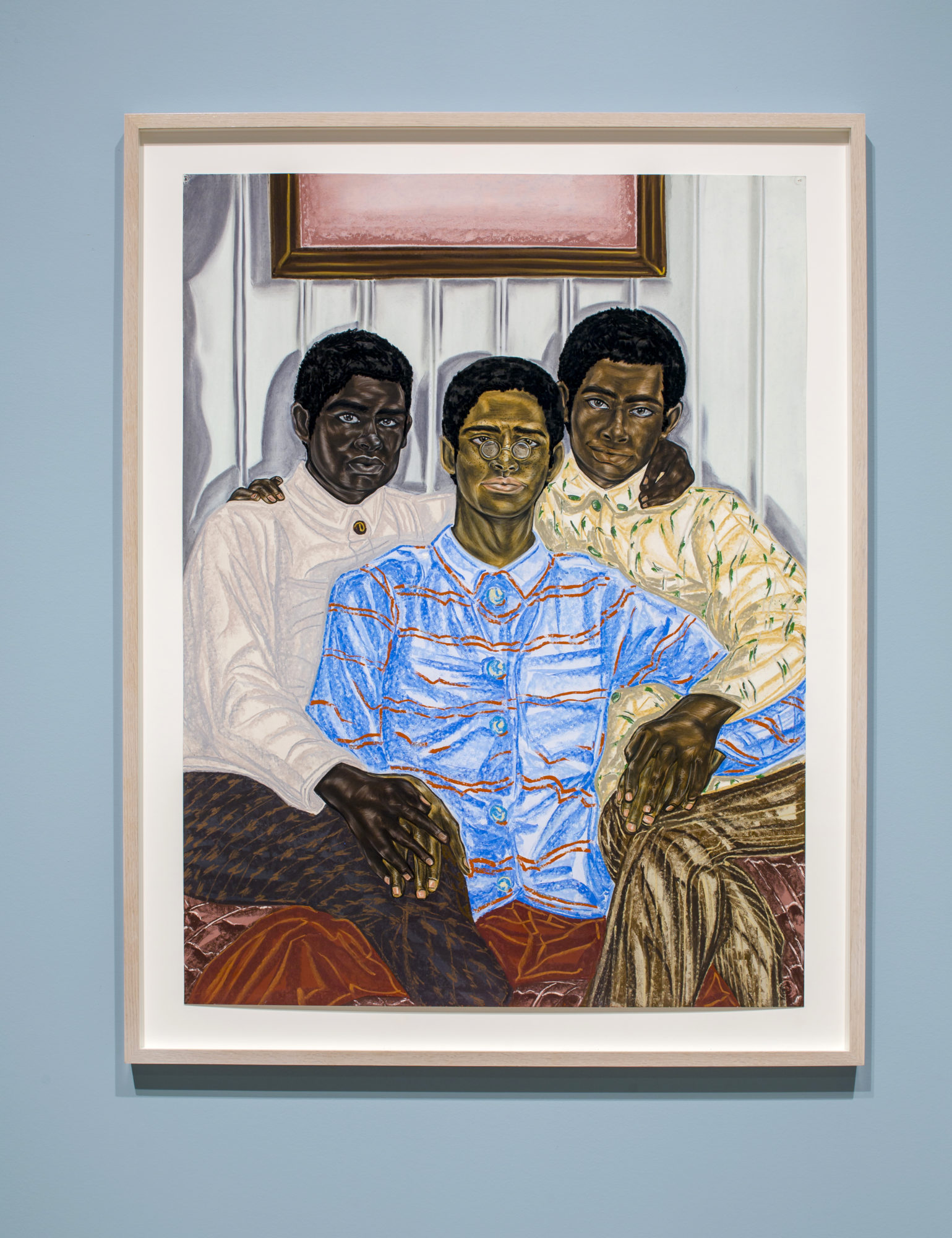 three men sitting together in front of a white wall