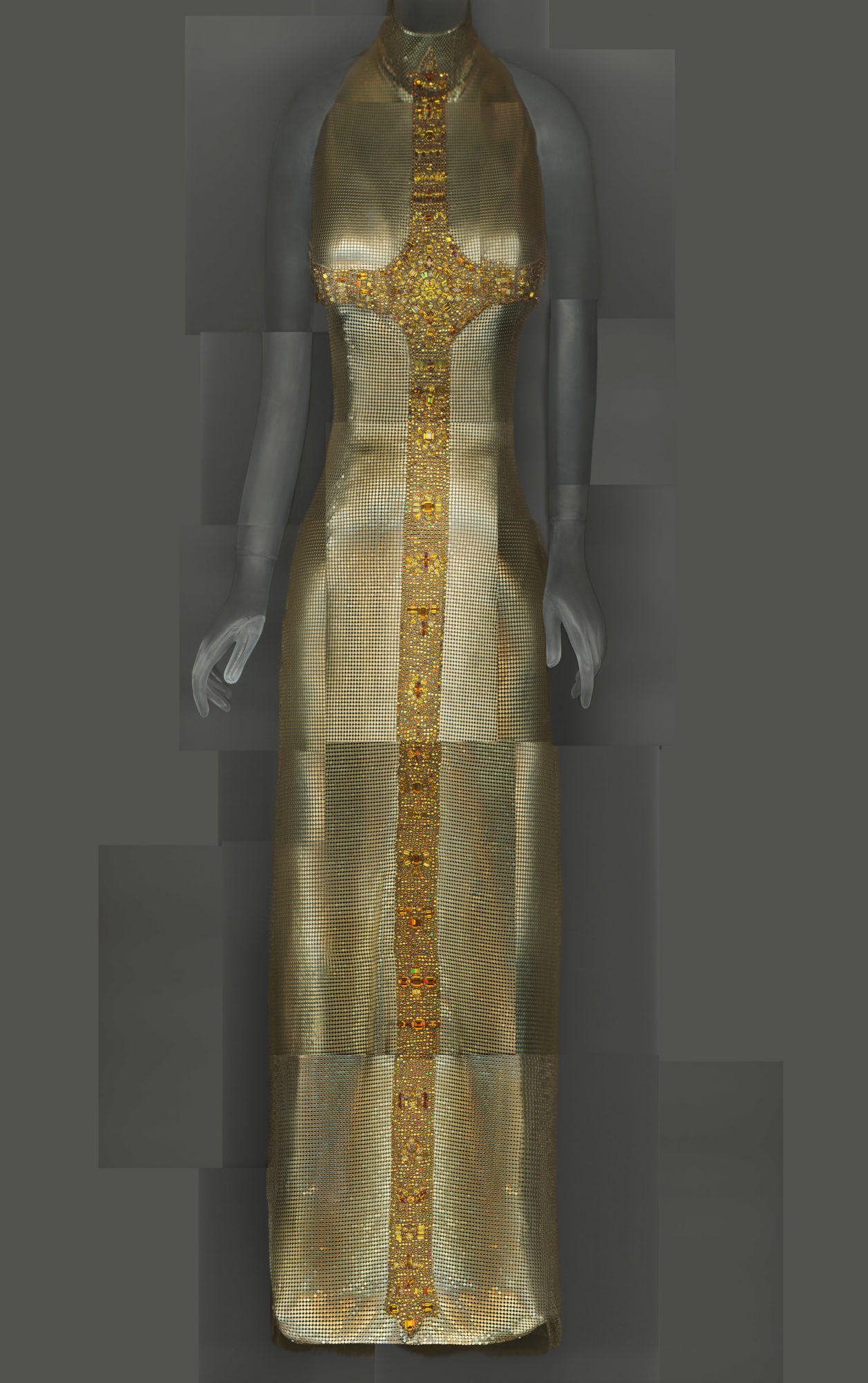 fitted, gold sleeveless gown with beadwork depicting a cross along the breast-line, and length of the body.