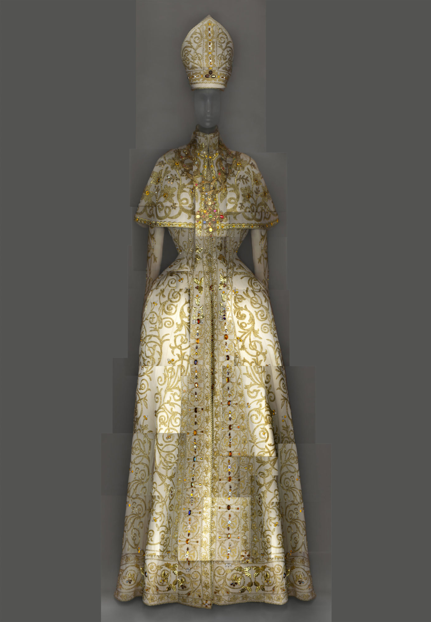 ivory gown with a gold pattern, cinched at the waist, and a hat shaped like a pope's traditional headwear.