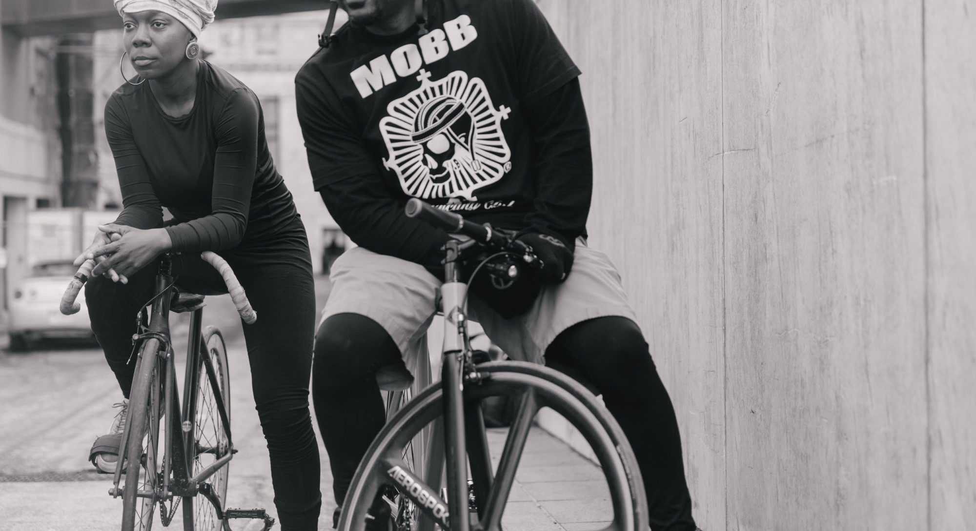 A black and white photo of a man and a woman posing on bikes