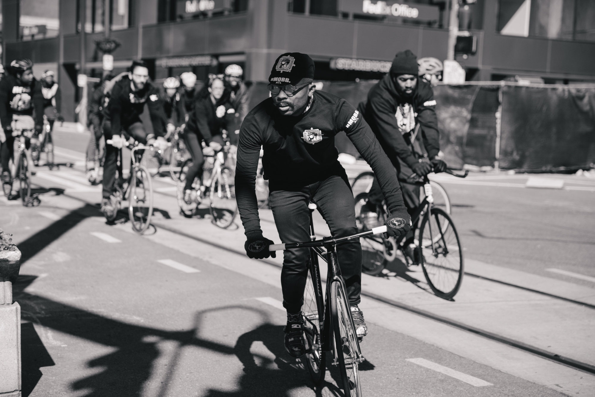 A black and white photo of a group of people of bicycles