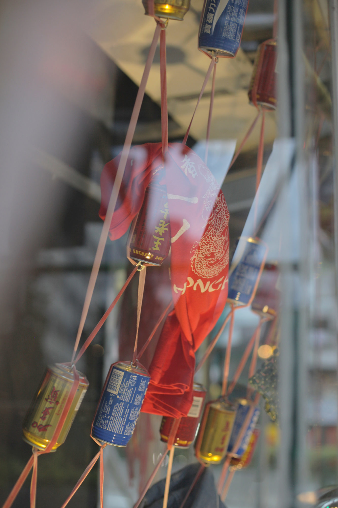 window display of colored cans held together by ribbon, with a red shirt draped across