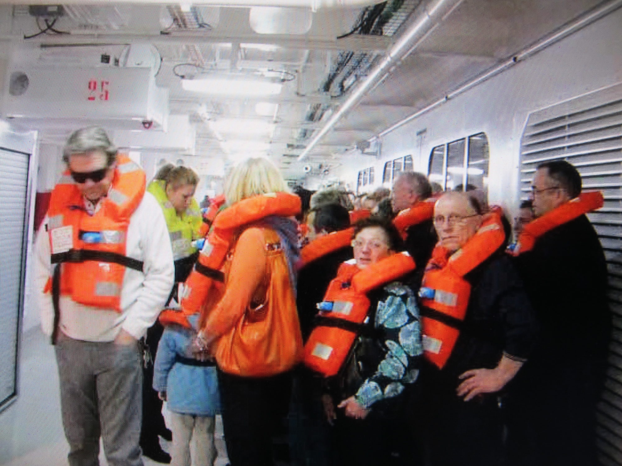group of people in a white space wearing orange life jackets