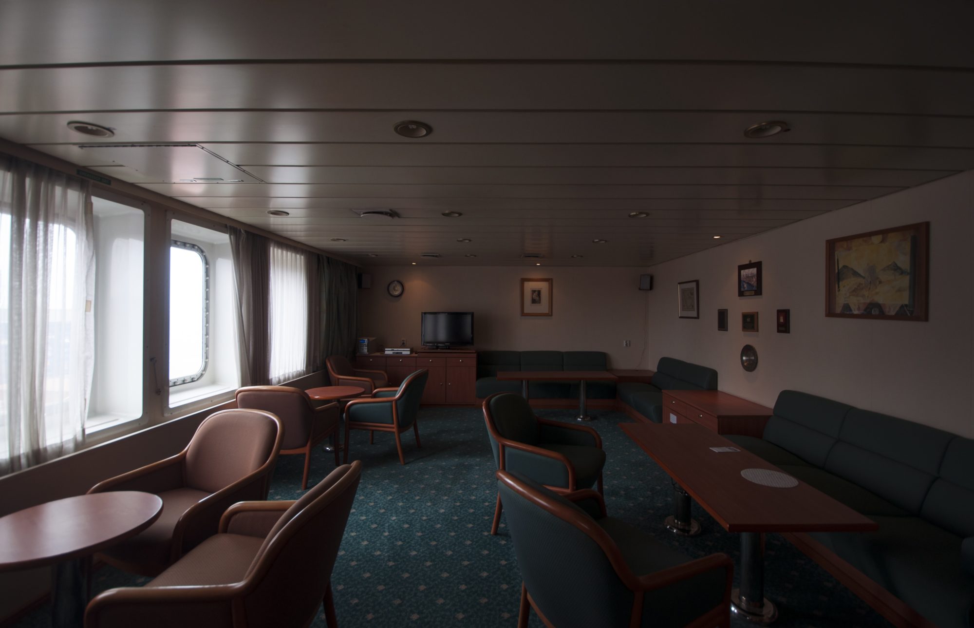 brown and teal cushioned chairs sit peacefully in an empty lounge with dim lighting