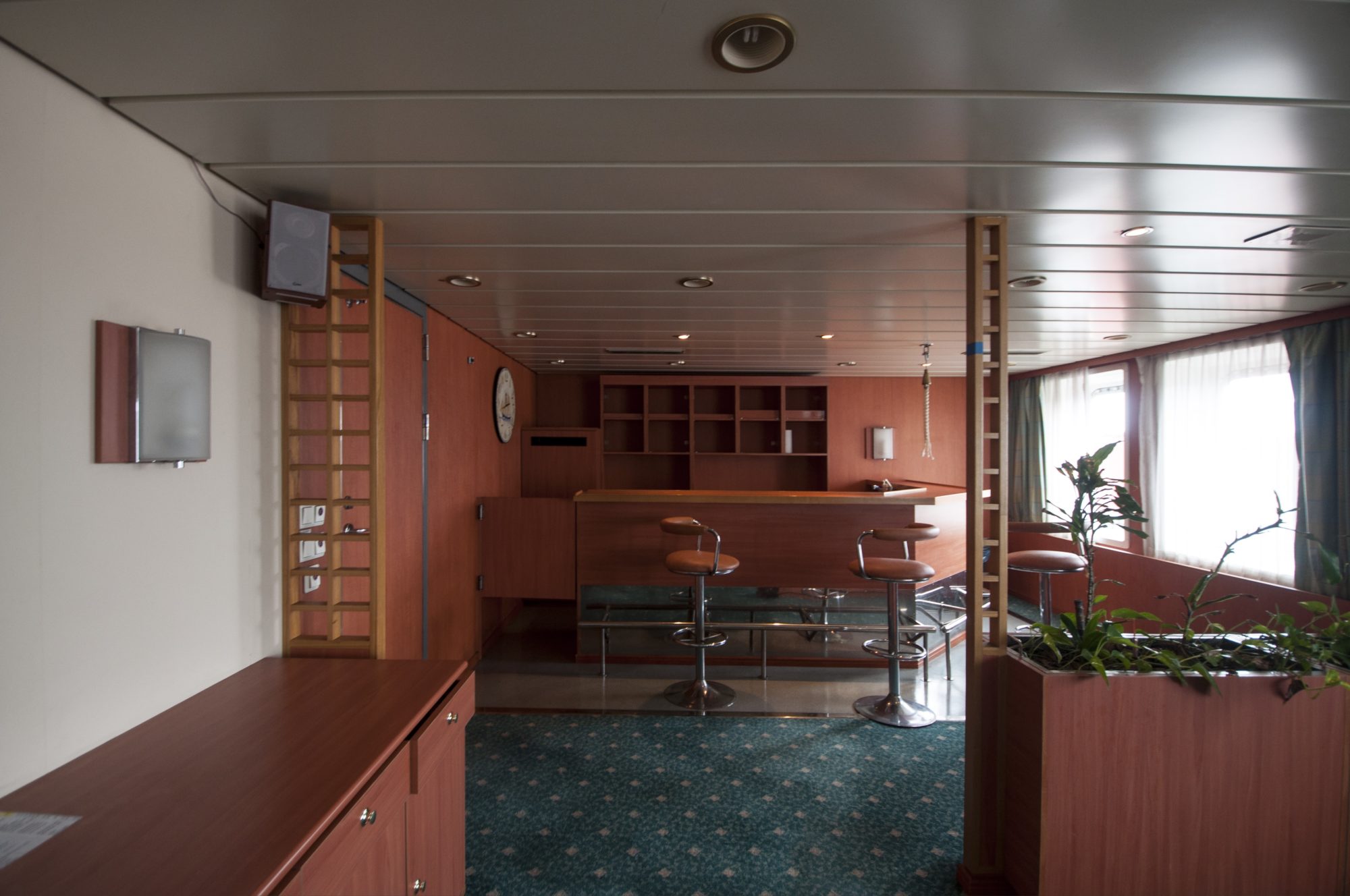 empty but not deserted bar aboard cargo ship; sunlight spills through window to the right near a curious and healthy plant