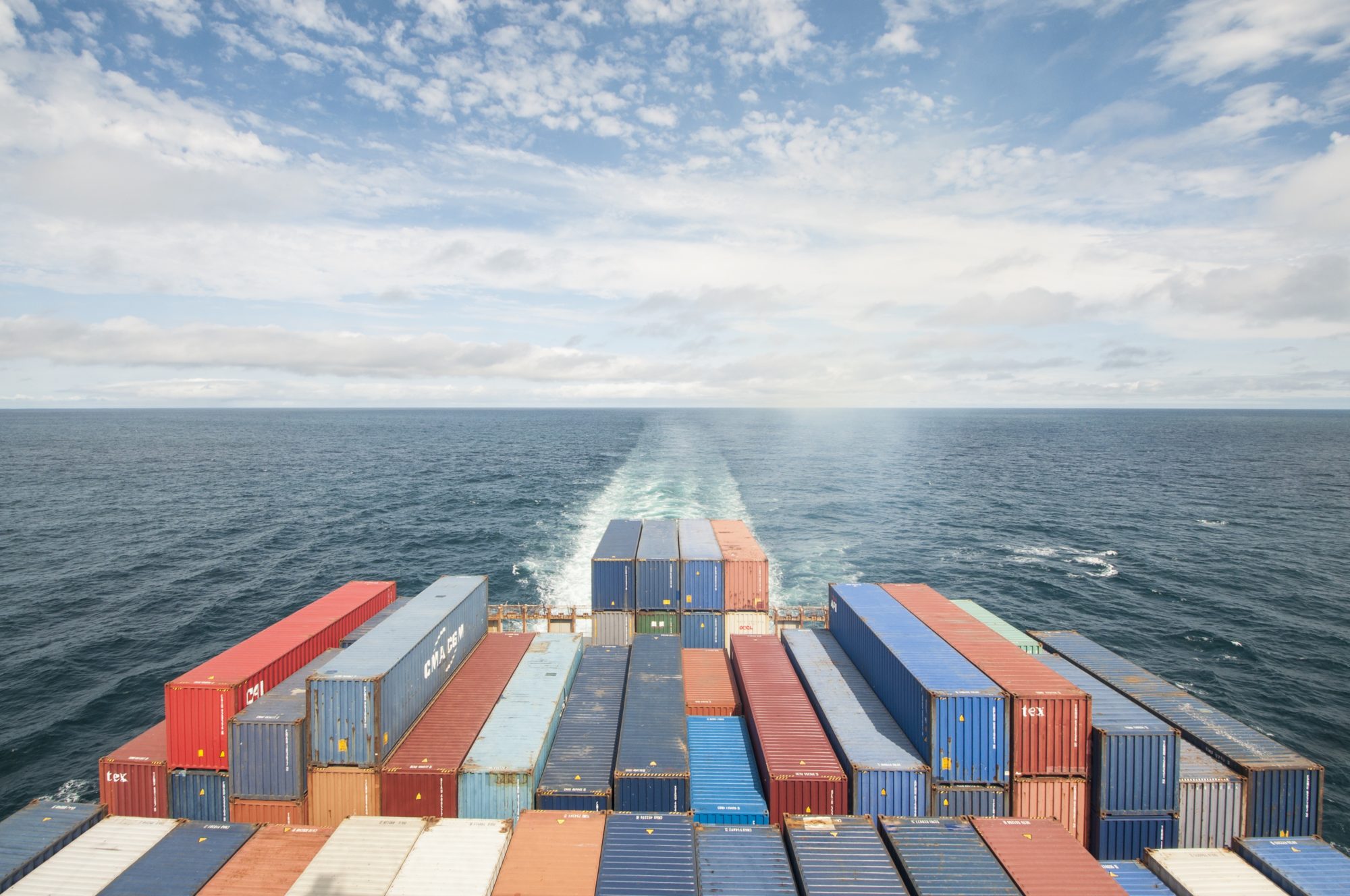 shipping containers of various colors being transported through water on a cargo ship