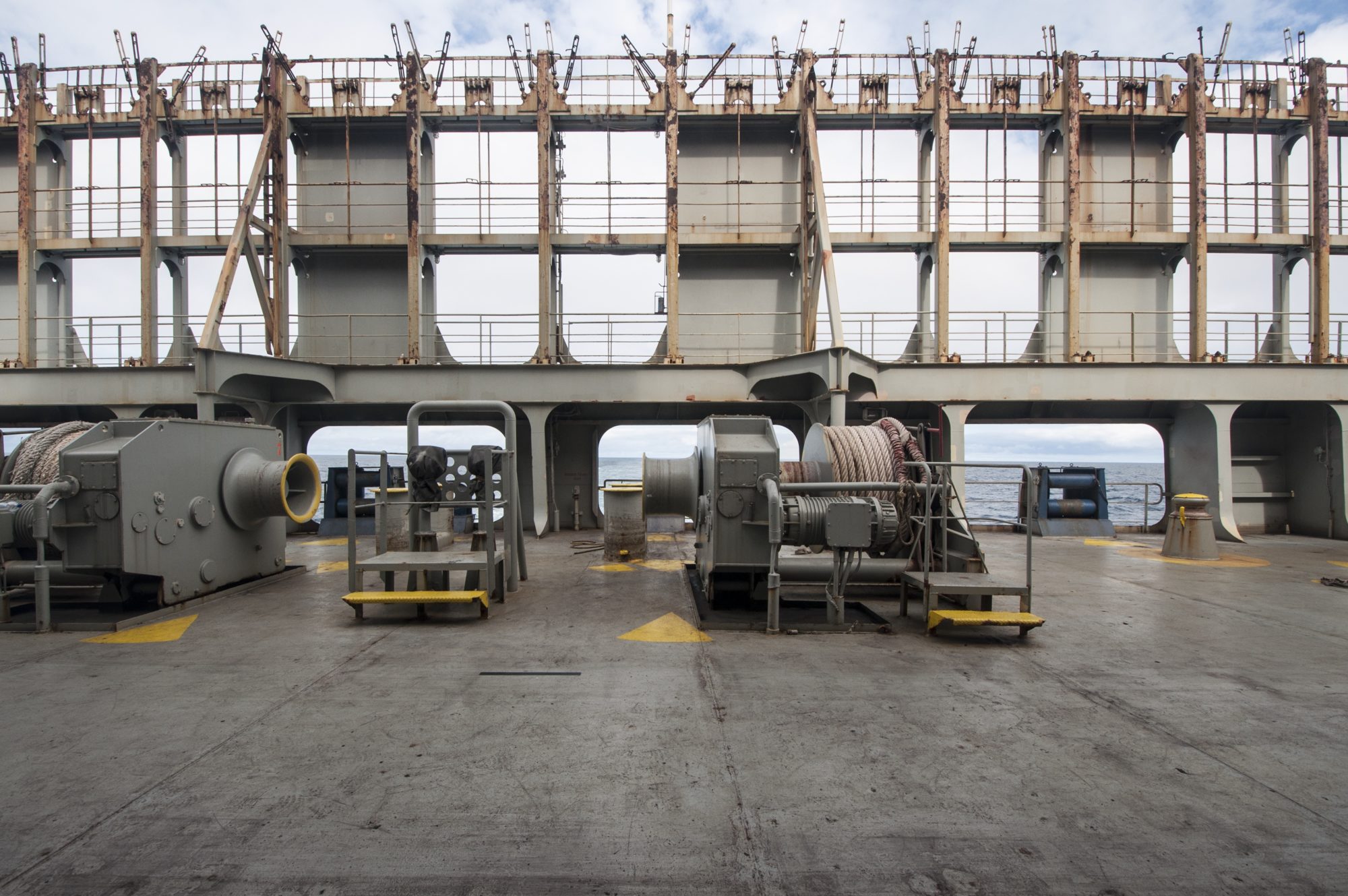 photo taken from cargo ship deck featuring walkways and cargo derricks