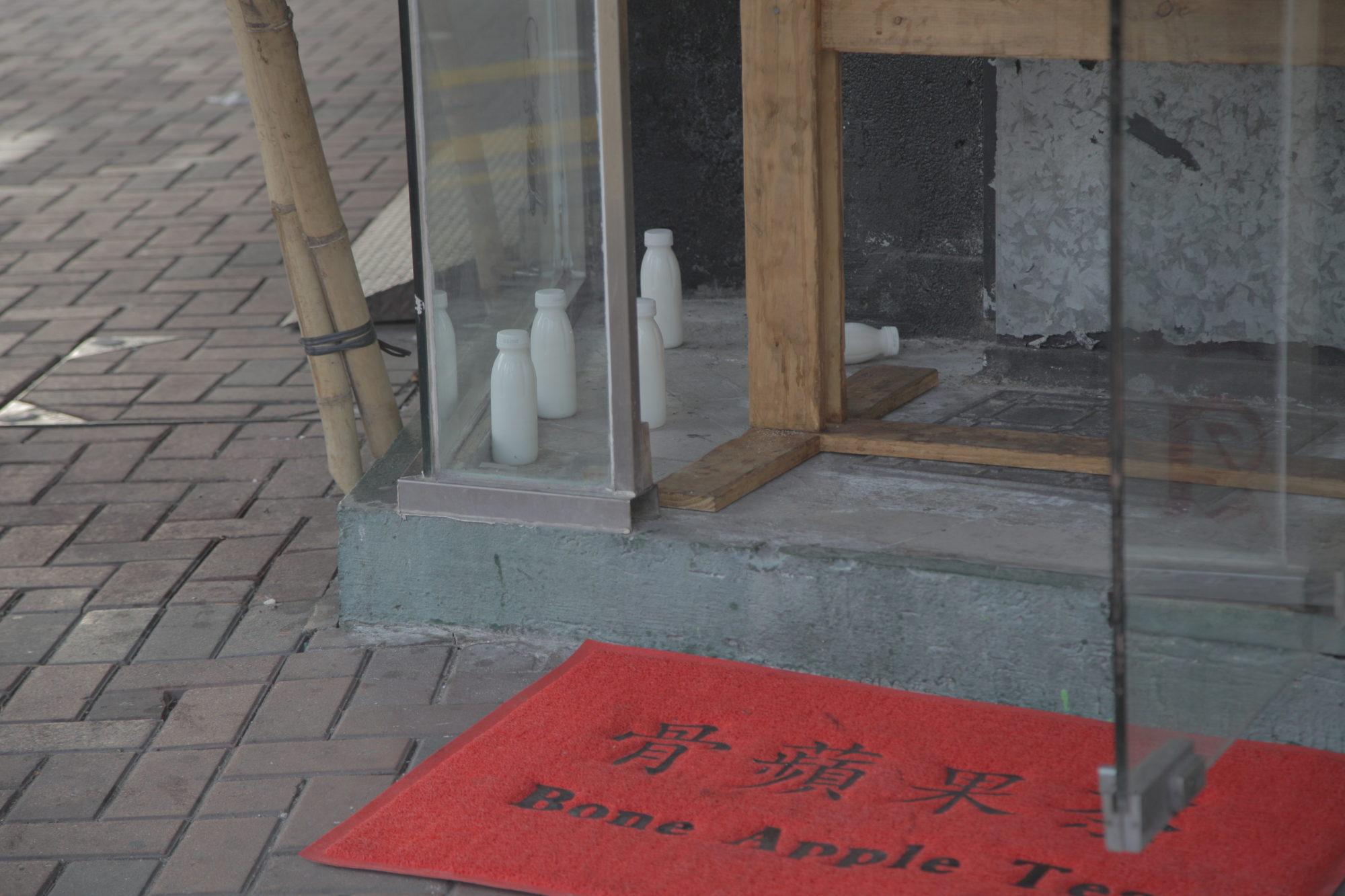 red doormat on brick sidewalk infant of a glass interior space with milk cartons