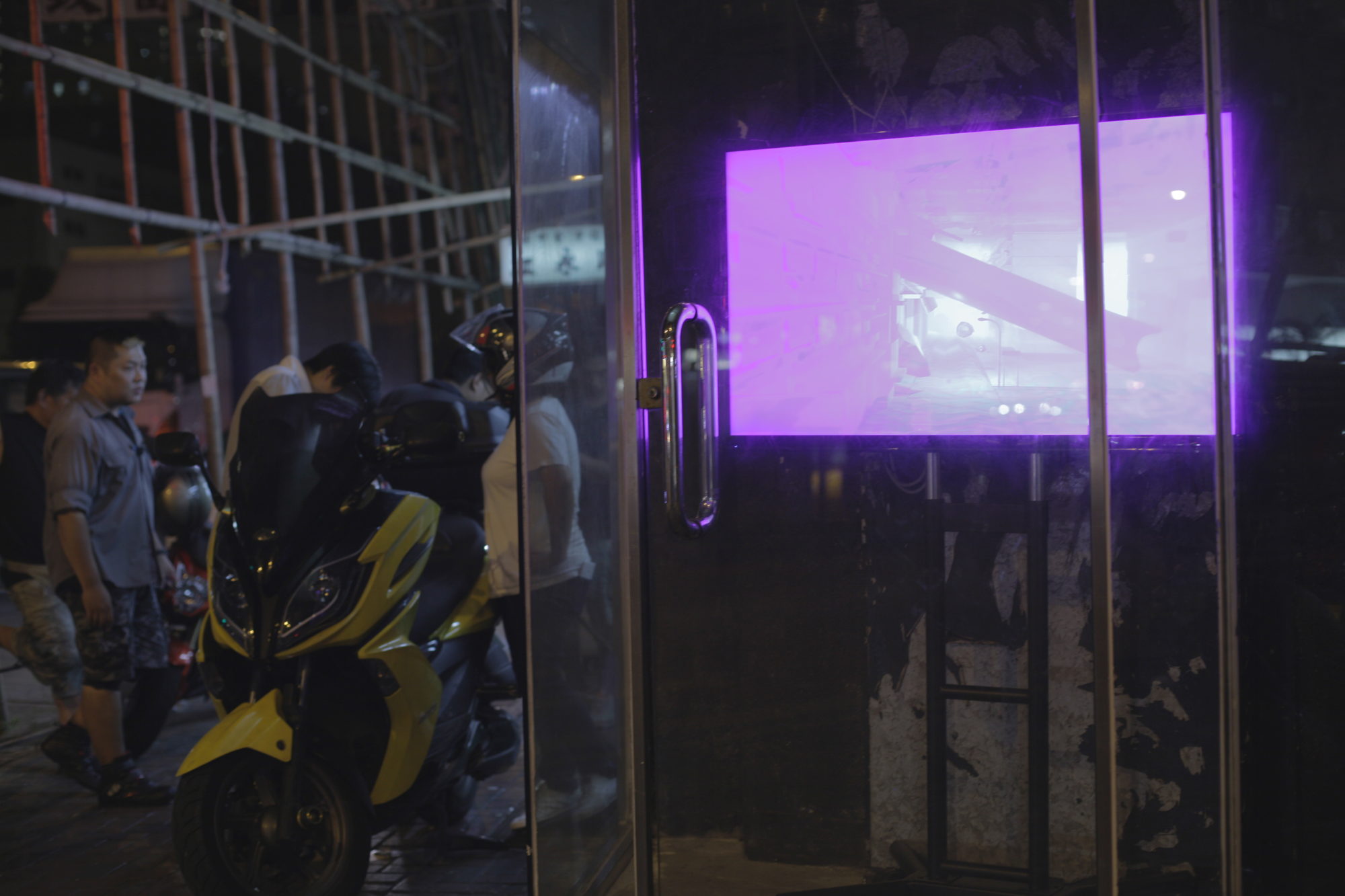 urban scene with a purple screen and a glass done next to people standing on the street next to a motorcycle