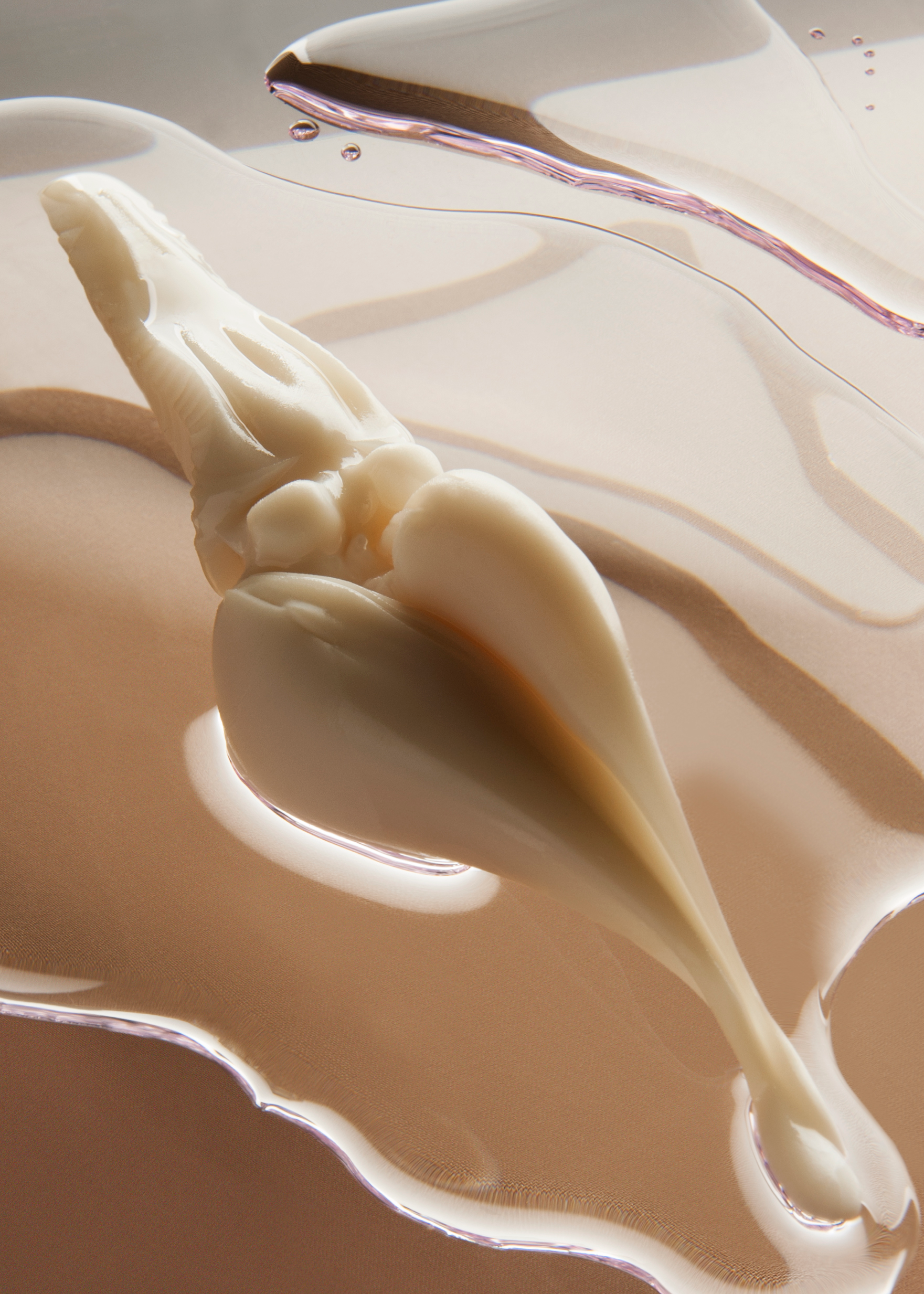 A milky-white floral figure overlays two puddles of shimmering liquid that rest upon a tan surface.