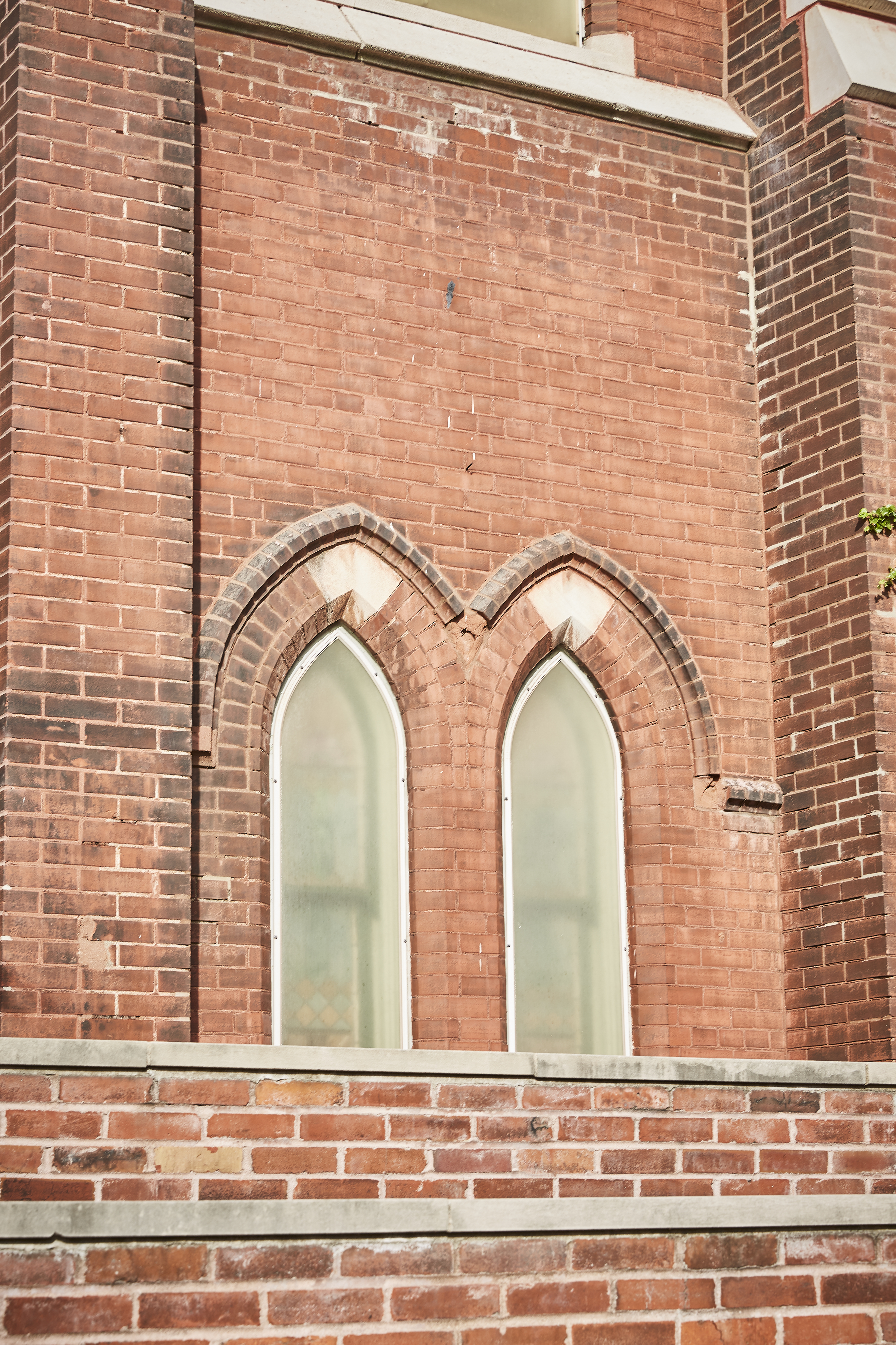 a brick building with two church-like windows in the center. the windows contain a cloudy, opaque glass.