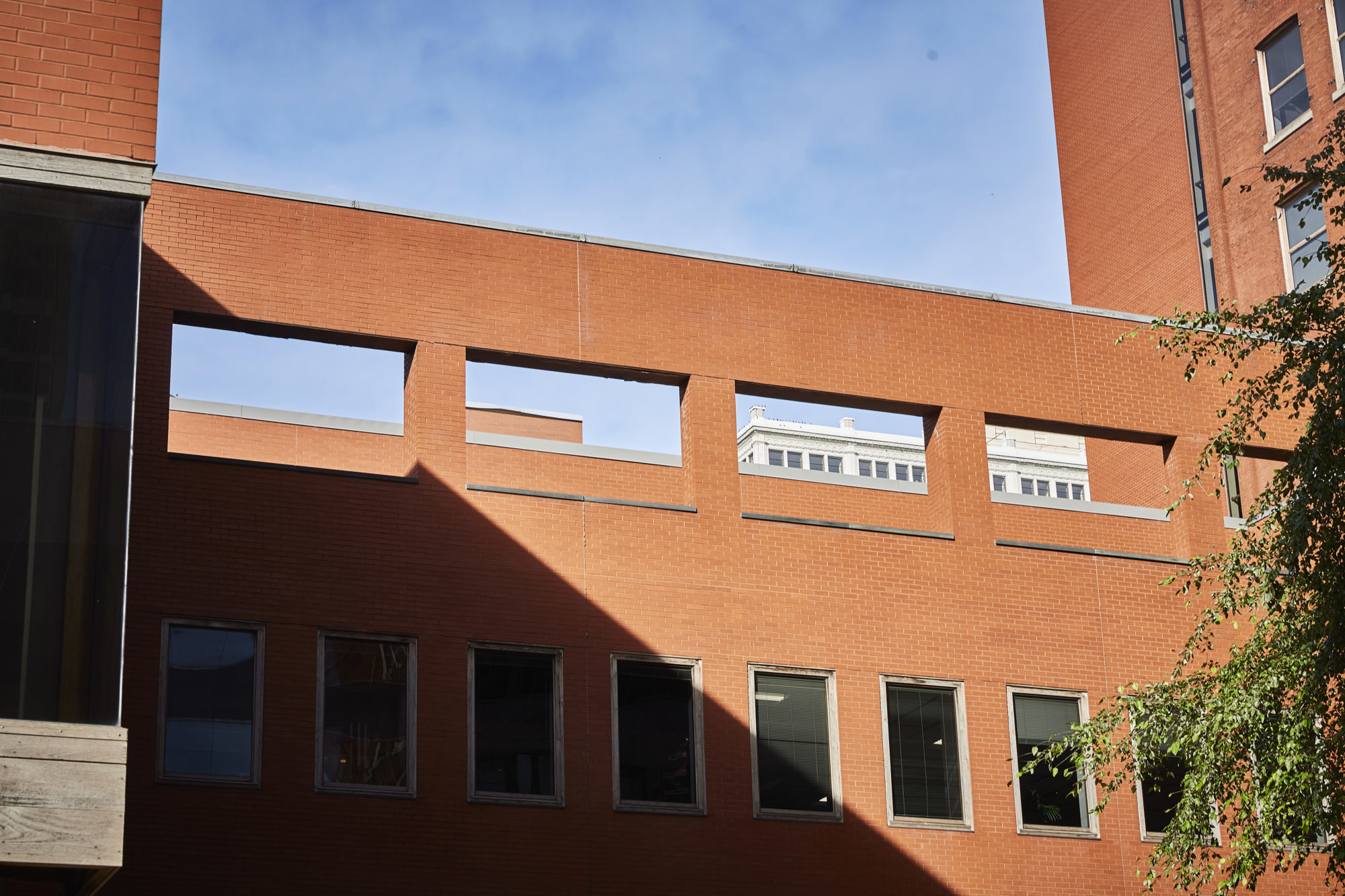 brick building against a blue sky with different sizes of rectangular windows