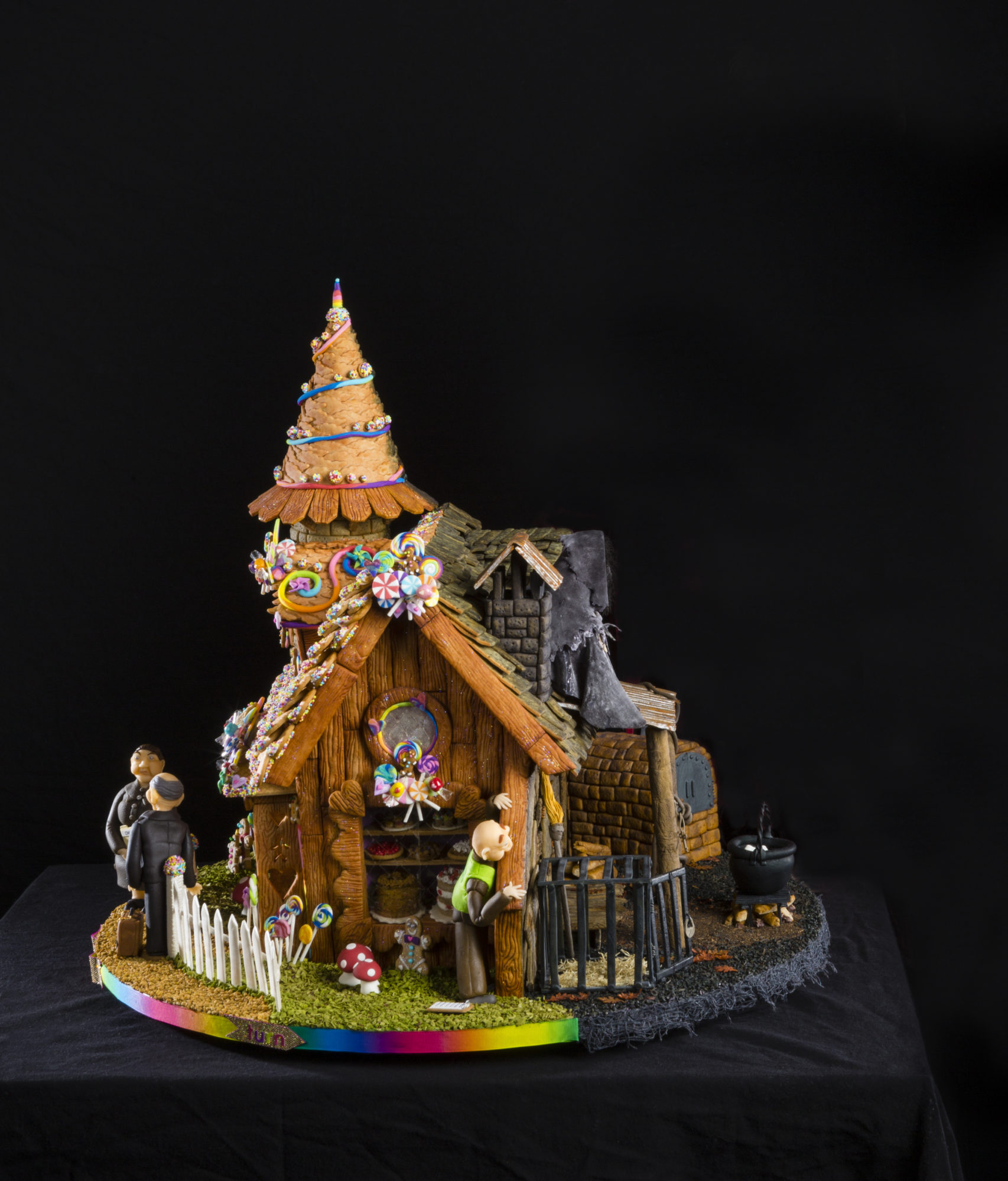 ornate gingerbread house with rainbow elements and three elderly figures