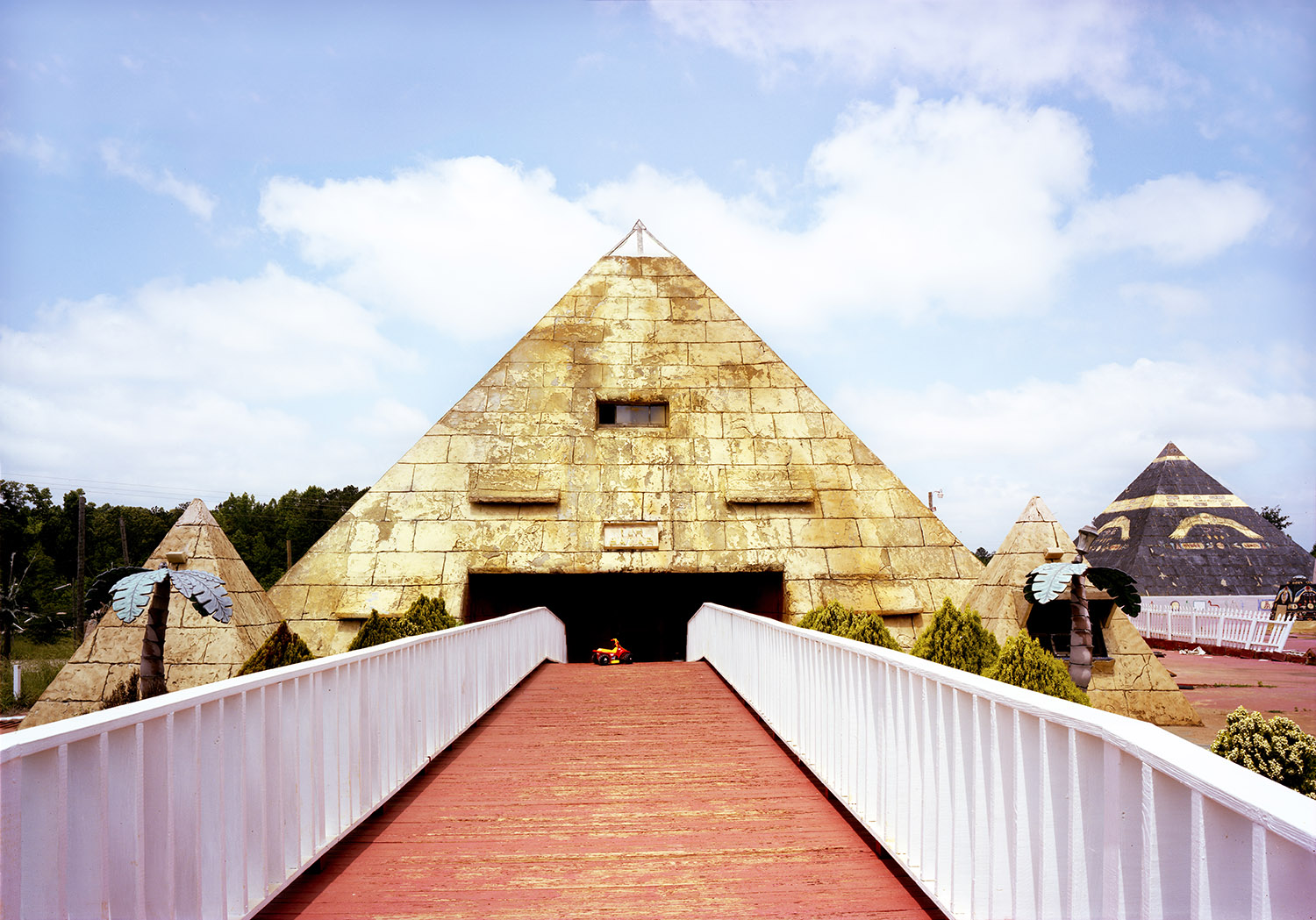 a red walkway leading to the mouth of a large golden pyramid. in the mouth of the pyramid in a toy truck.