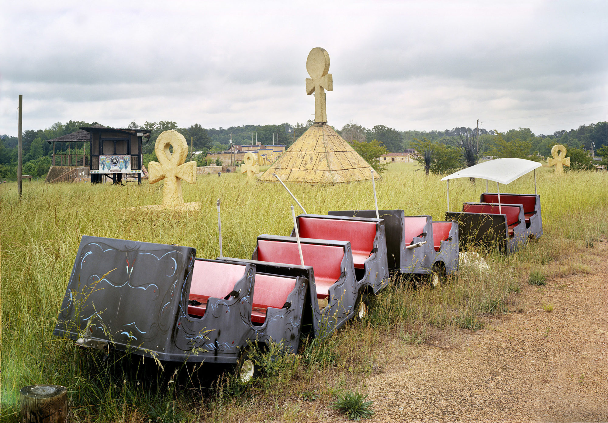 red and black booths on wheels but abandoned in a field with large, Egyptian cross symbols