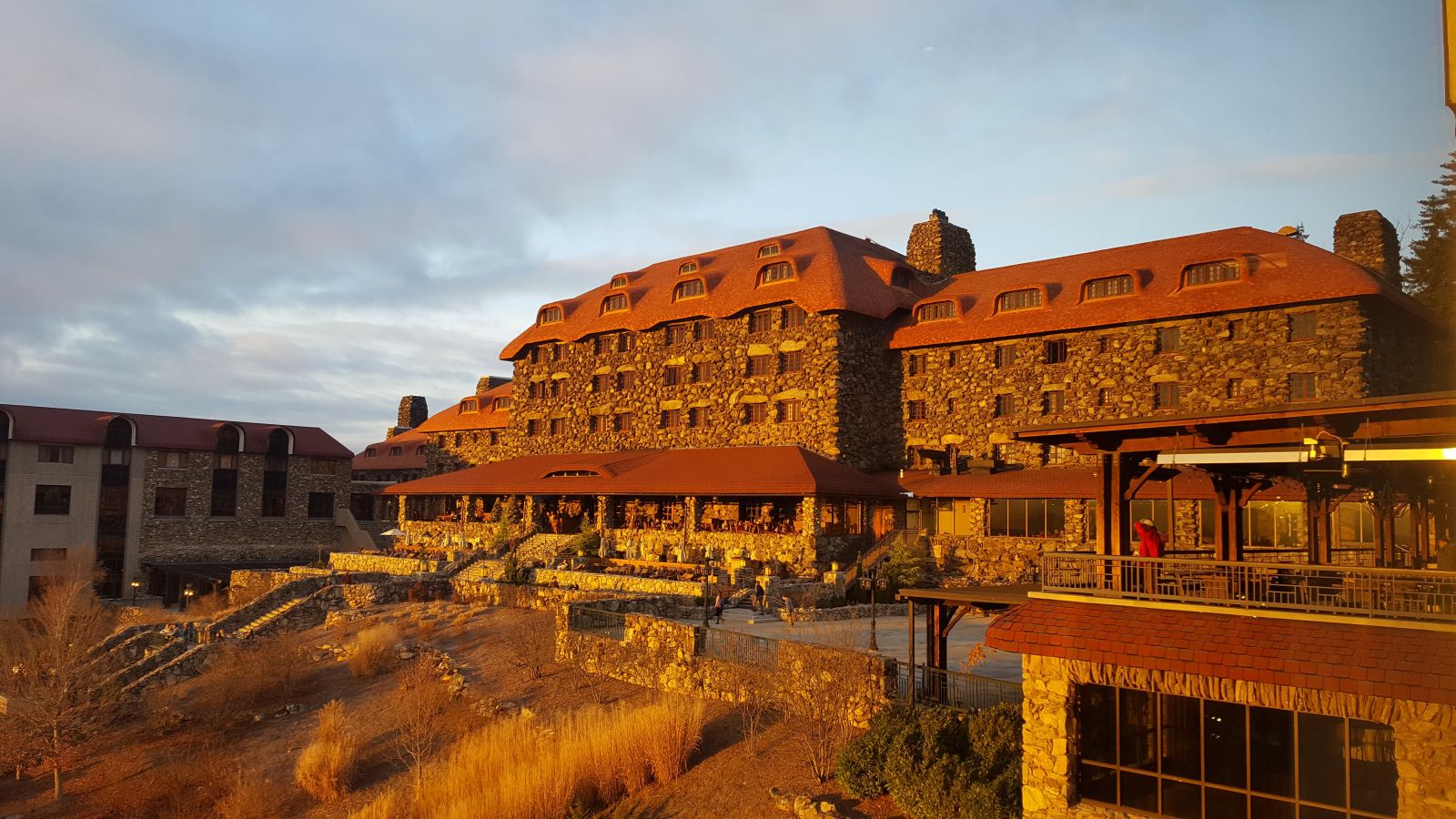 large, stone-walled hotel with an orange roof in the sunlight