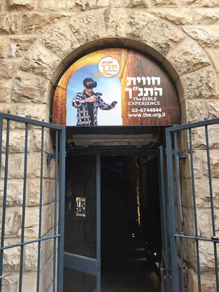 A photograph of a doorway with a sign above it advertising a virtual reality Bible Experience.