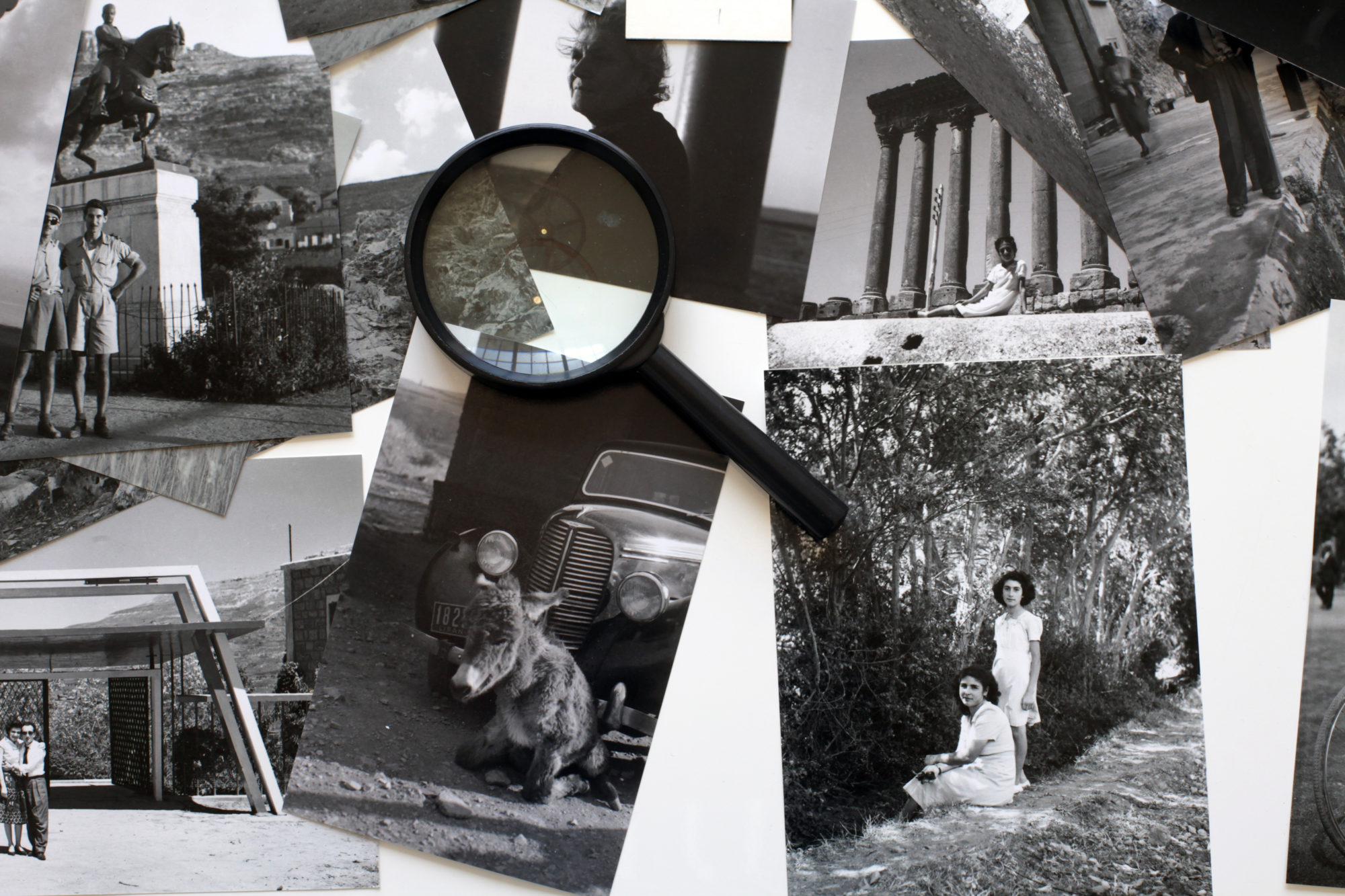 An image of a series of black and white photographs with magnifying glass in the center