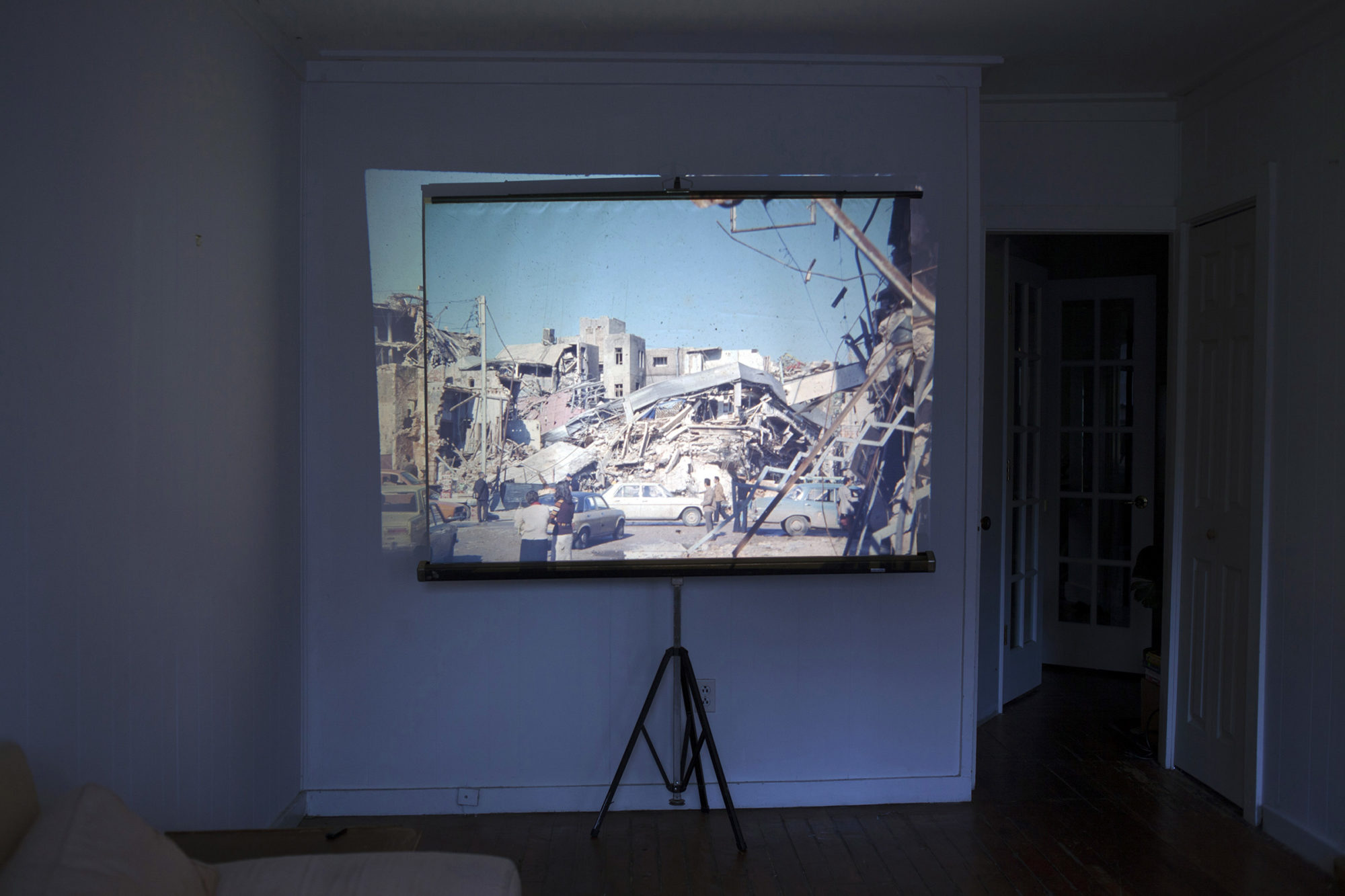 A photo of a screen with an image projected on it against white wall in a room