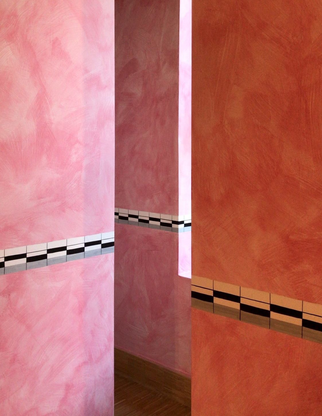 corner views of several pink and salmon walls. white, black, and gray rectangles form a stripe in the center of the walls.