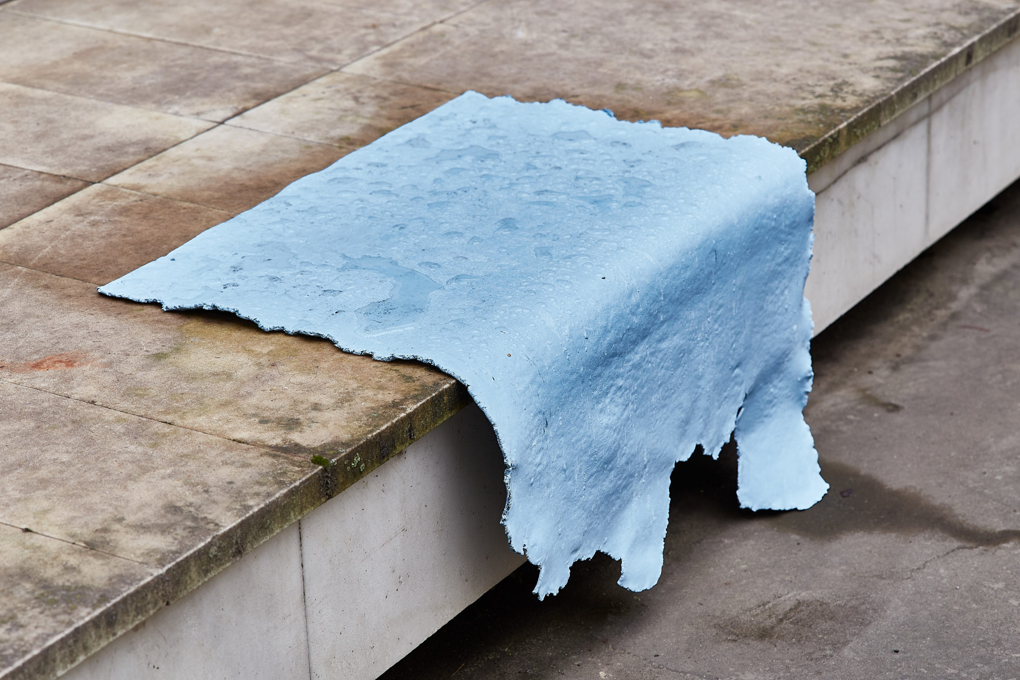 light blue flat piece of rubber hanging off side of tile floor