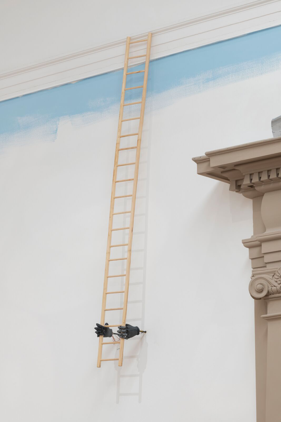 a ladder that enters through the ceiling and has two black hands holding it at the bottom