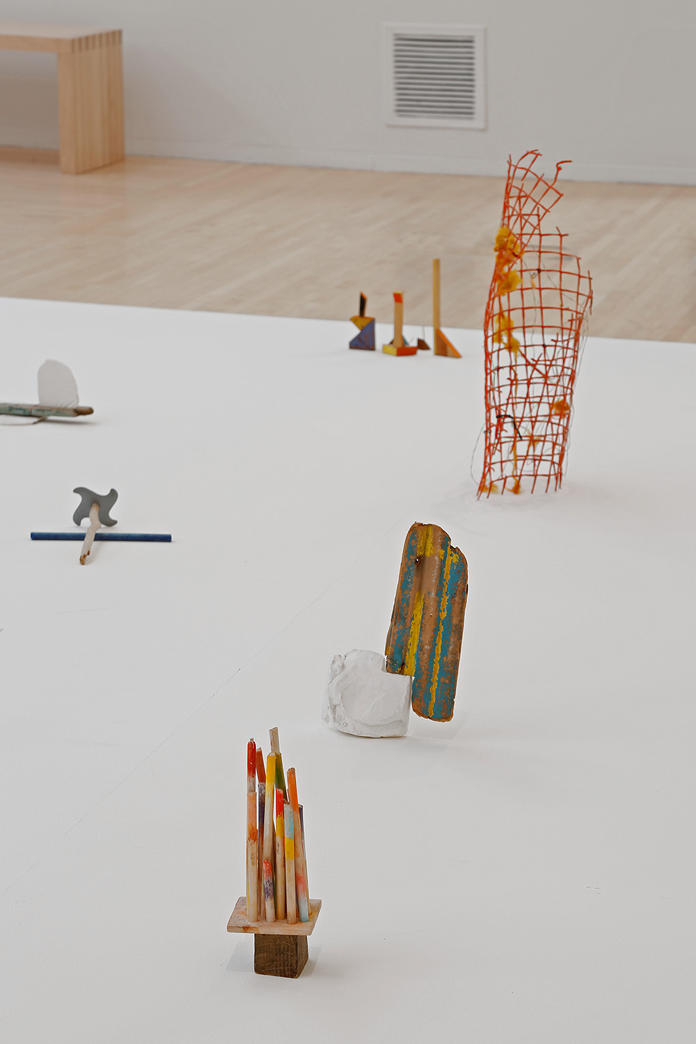 Multiple small sculptures are set on a painted, white floor