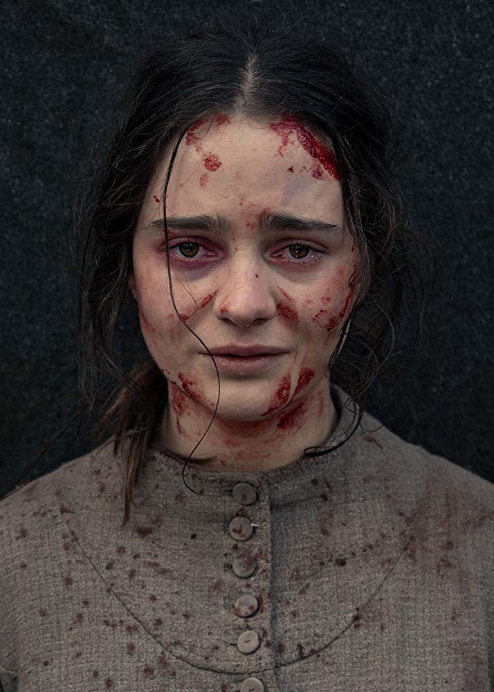 A close up of a scared women with dried up blood on her face and clothing